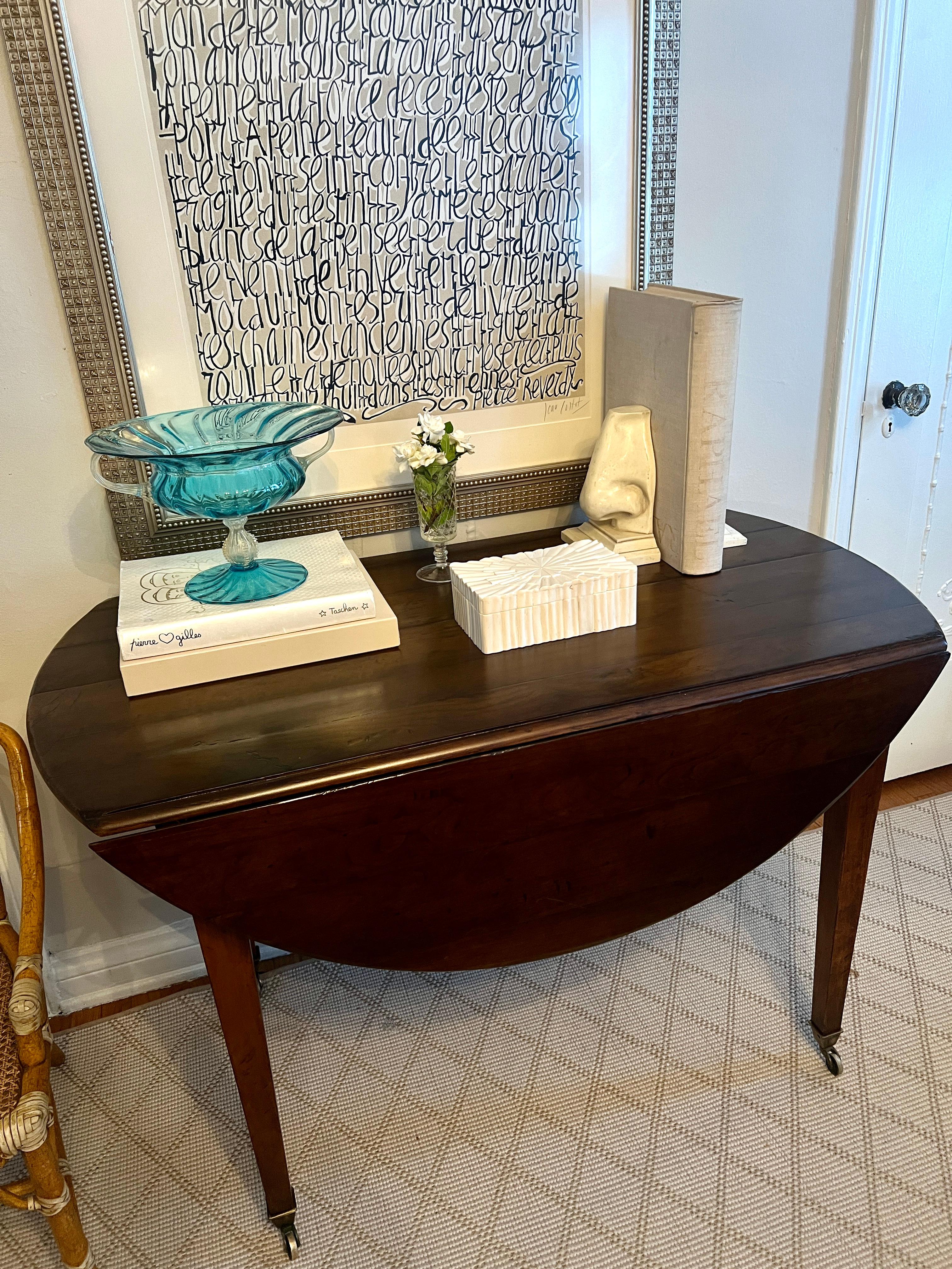 Une table à feuilles tombantes Directoire magnifiquement fabriquée à la main avec des sabots/roues en laiton.  Facile à déplacer d'une pièce à l'autre.

Sa taille pratique est parfaite pour un petit espace car elle peut servir de table console, et