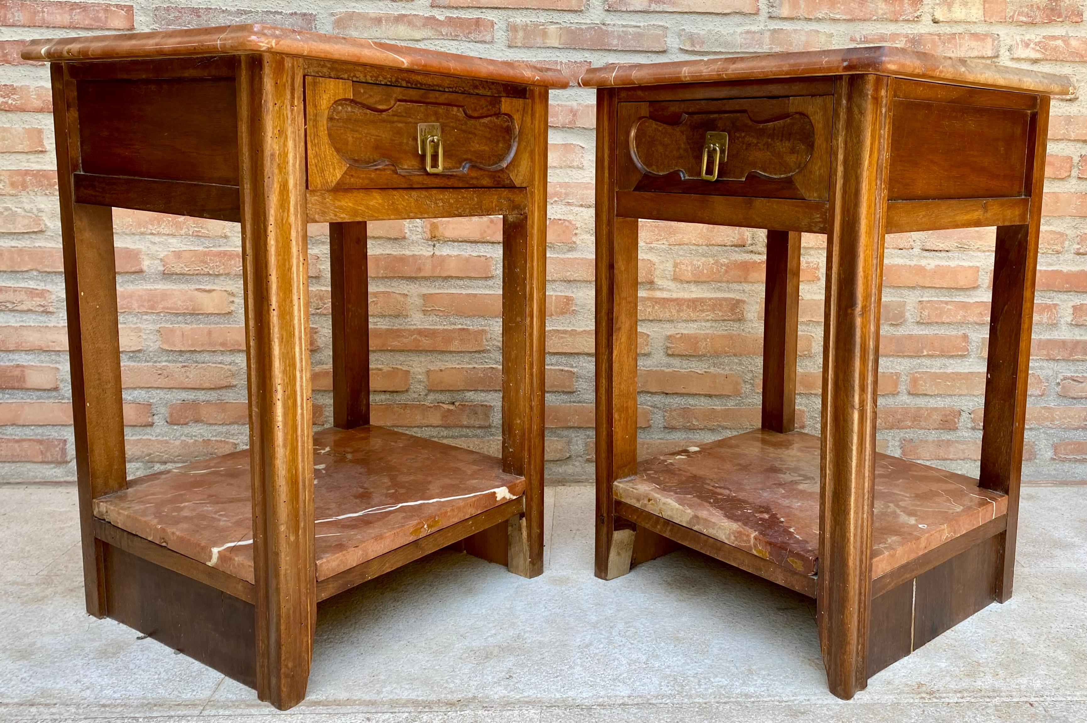 Beautiful pair of bedside tables from the 40s in art deco style. They have a low shelf of reddish marble, and their top supported by four straight columns also have a marble base of the same color.
They also have a small carved front drawer with