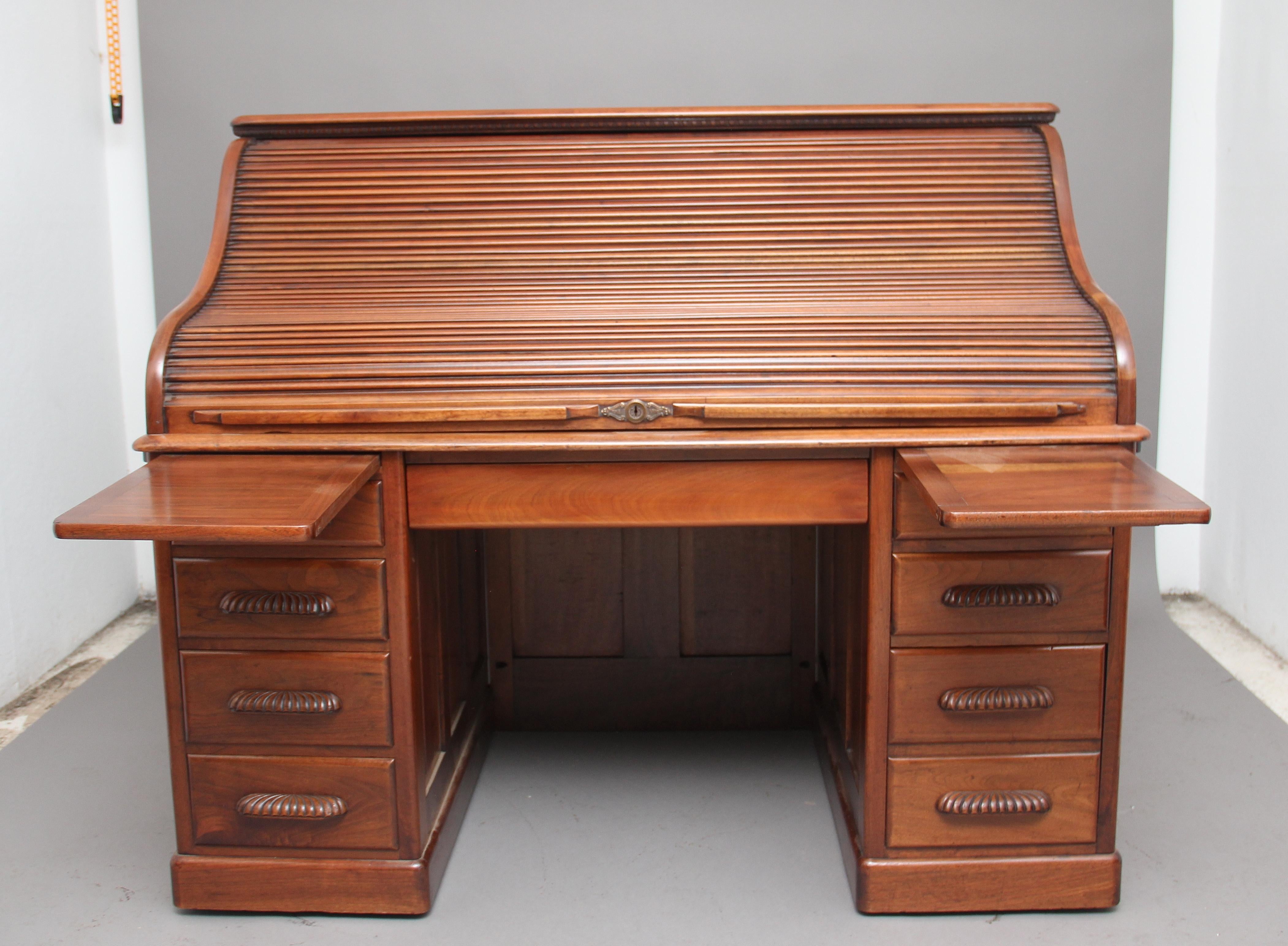 Early 20th century walnut roll top desk, the molded edge top with decorative carved beading underneath, the tambour roller top opening to reveal a selection of drawers, pigeon holes, compartments and a large writing surface, below there is a frieze
