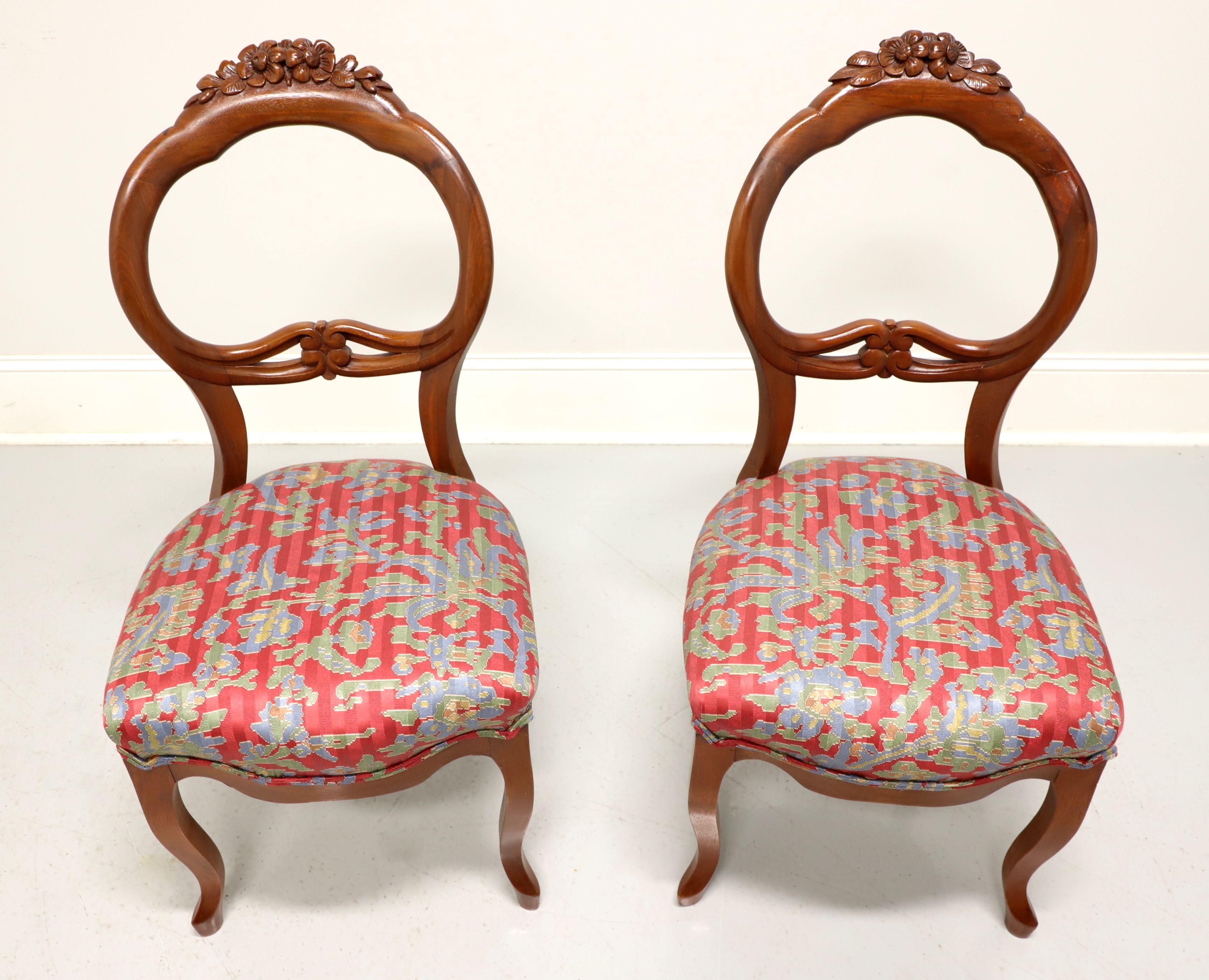 A pair of antique Victorian balloon back side chairs, unbranded. Walnut with decorative floral carving to crest rail, carved backrest, multi-color floral fabric upholstered seat and cabriole legs. Likely made in the USA, in the early 20th