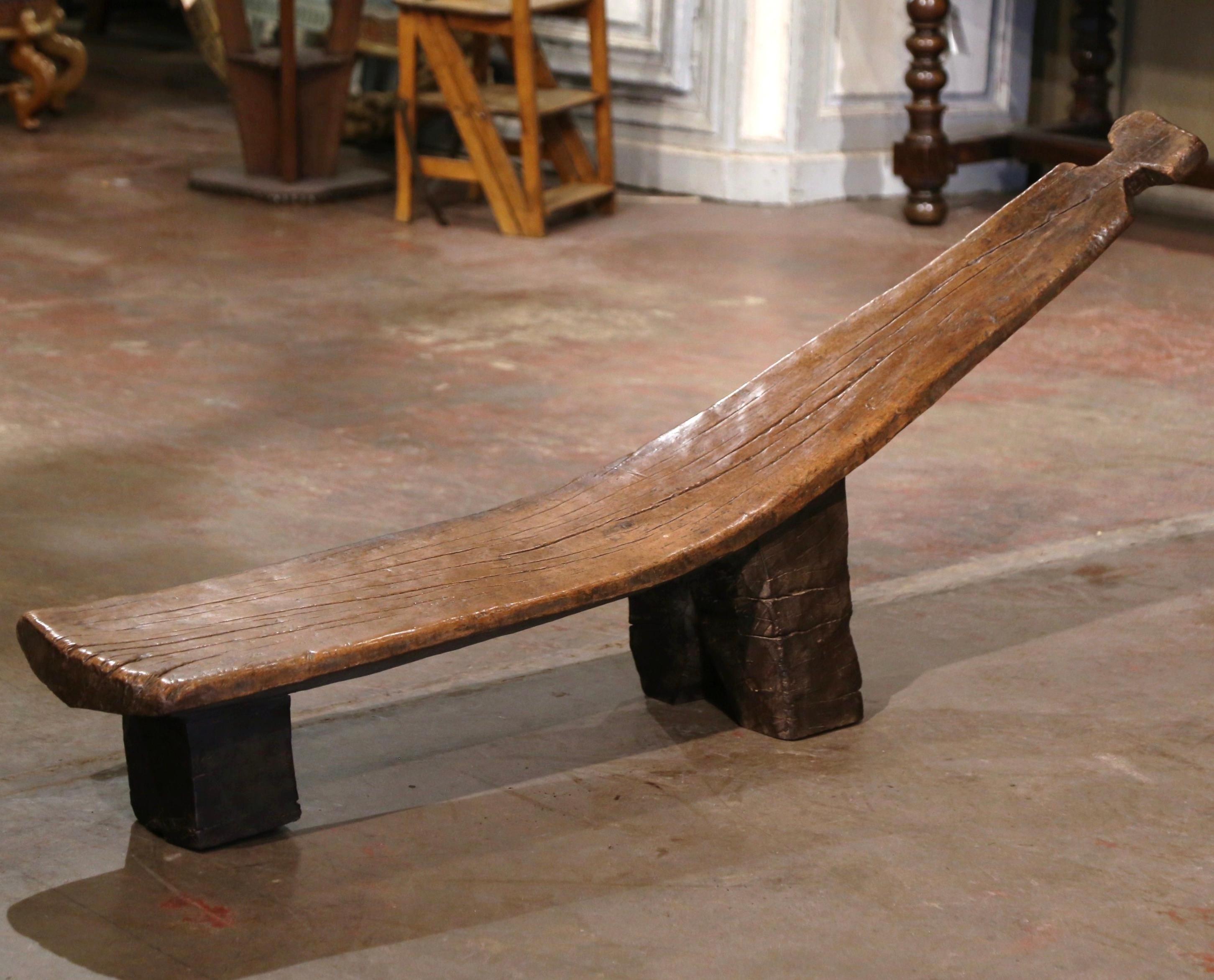 Decorate a den or game room with this elegant antique tribal bench. Hand carved in western Africa, and attributed to the Senufo tribe, the bench is naturally curved and stands on two carved legs. The seat is made of one single piece of indigenous
