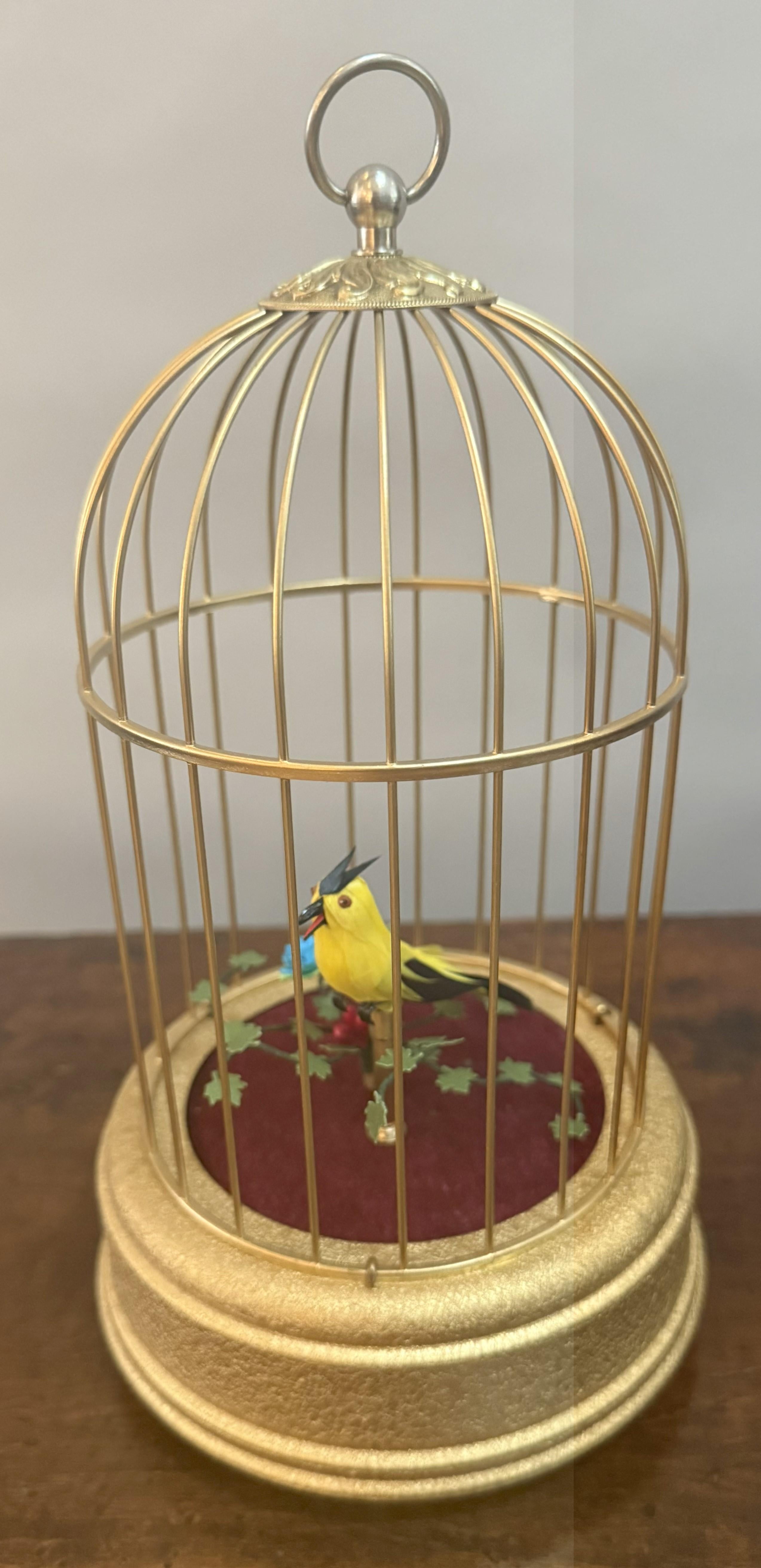 An enchanting jewel of mechanical artistry! This early 20th-century singing bird automaton evokes the romance of Europe's golden age of craftsmanship. Encased within an elegantly domed gilded brass cage with an ornate acanthus-cast finial and richly