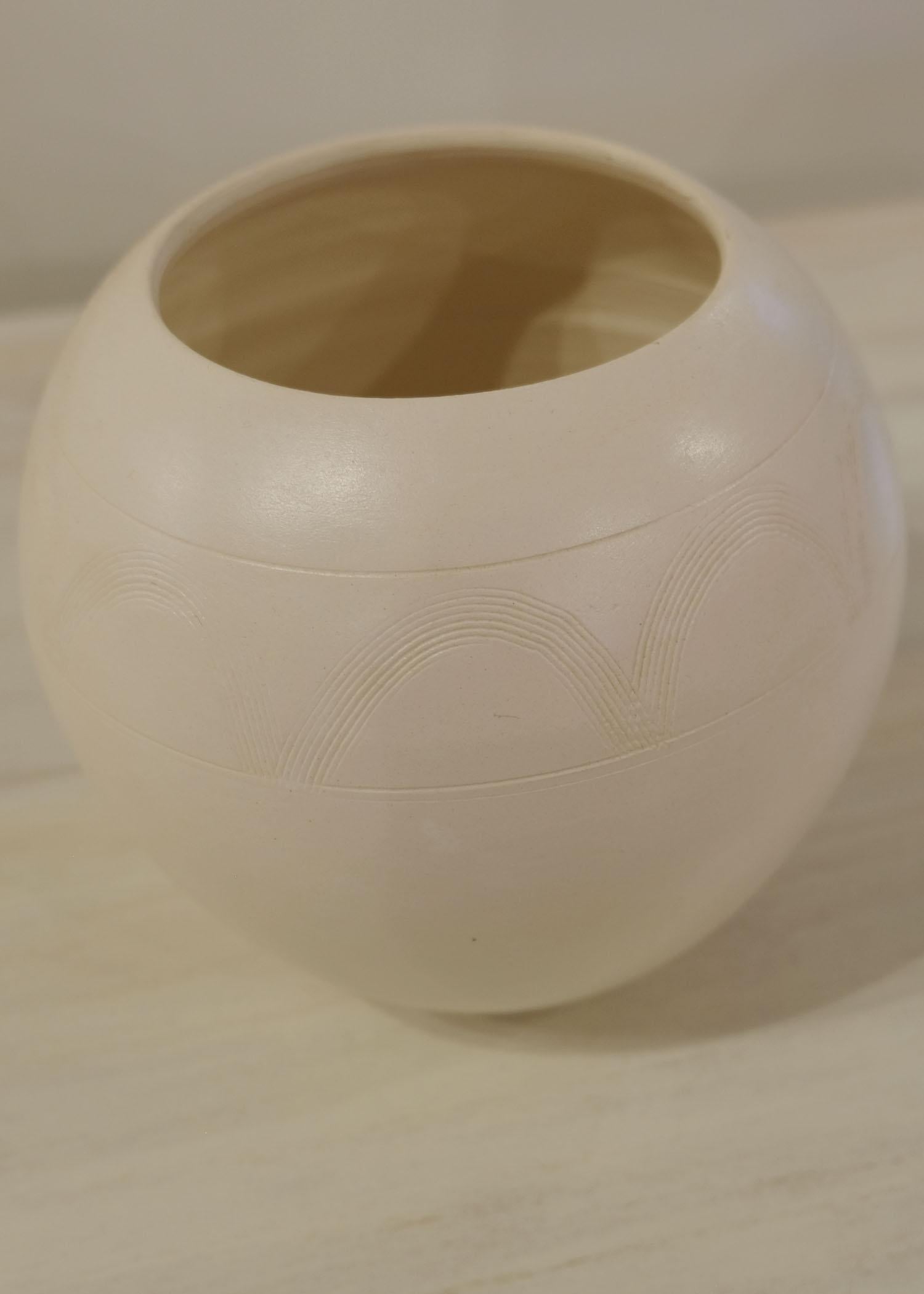 White clay zulu pot with intricate arch carvings.