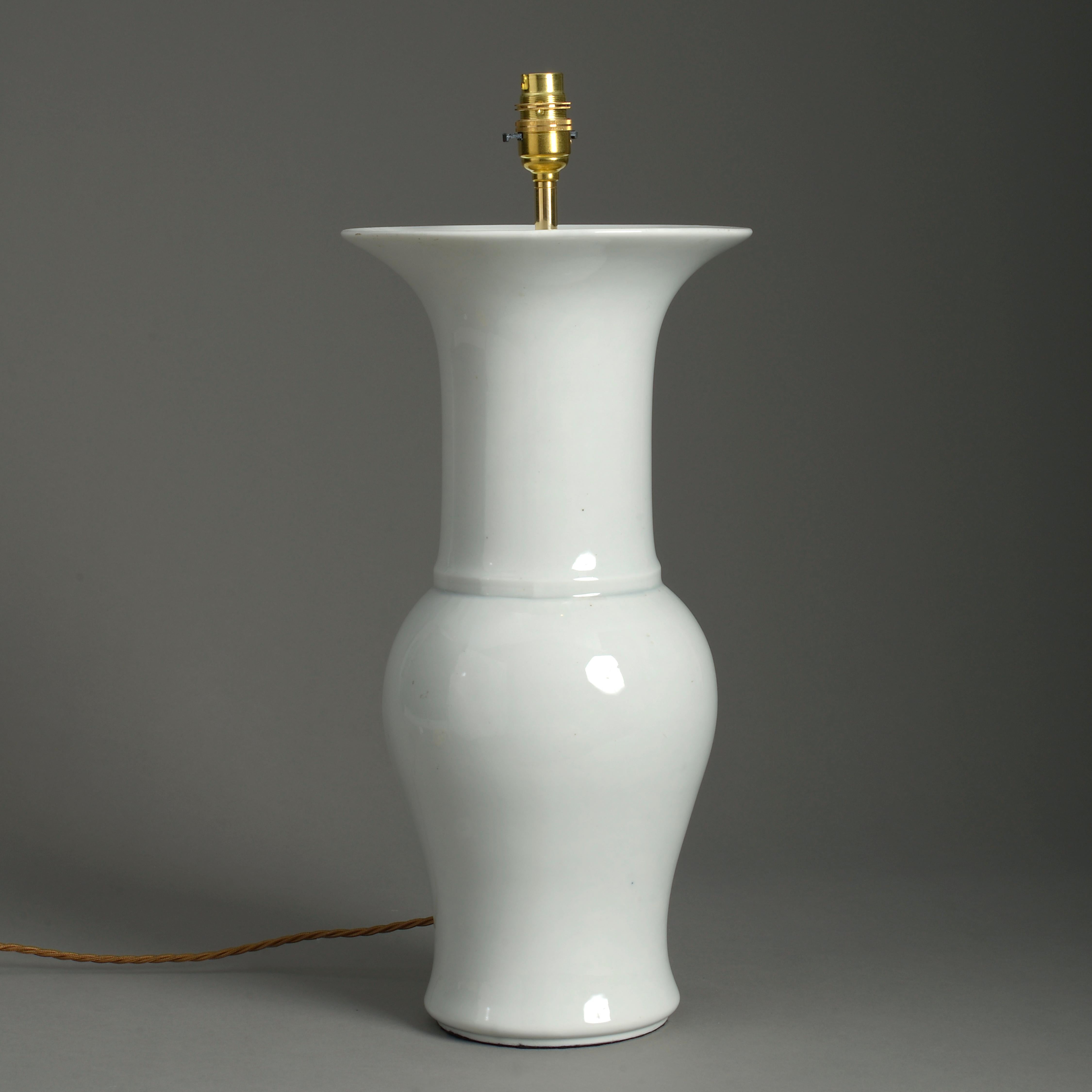 An early 20th century white porcelain sleeve vase, the trumpet neck above a baluster body. Now wired as a table lamp.

Dimensions refer to height of vase and base only.

Wired and tested for UK standards. This piece can be re-wired for US, EU