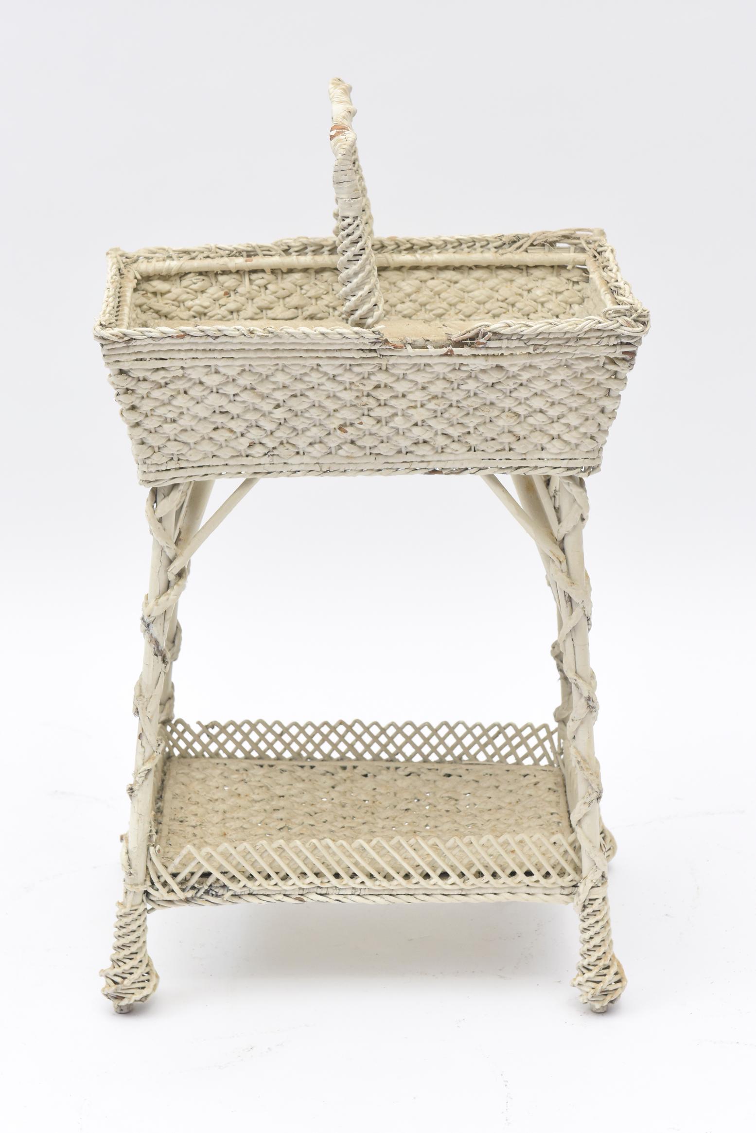 Part of a large collection of ornate wicker that was collected over the years by a Senator's wife. Early 20th century, the open sewing basket has a woven lattice gallery bottom shelf and woven wicker with twisted wicker encircling the legs as they