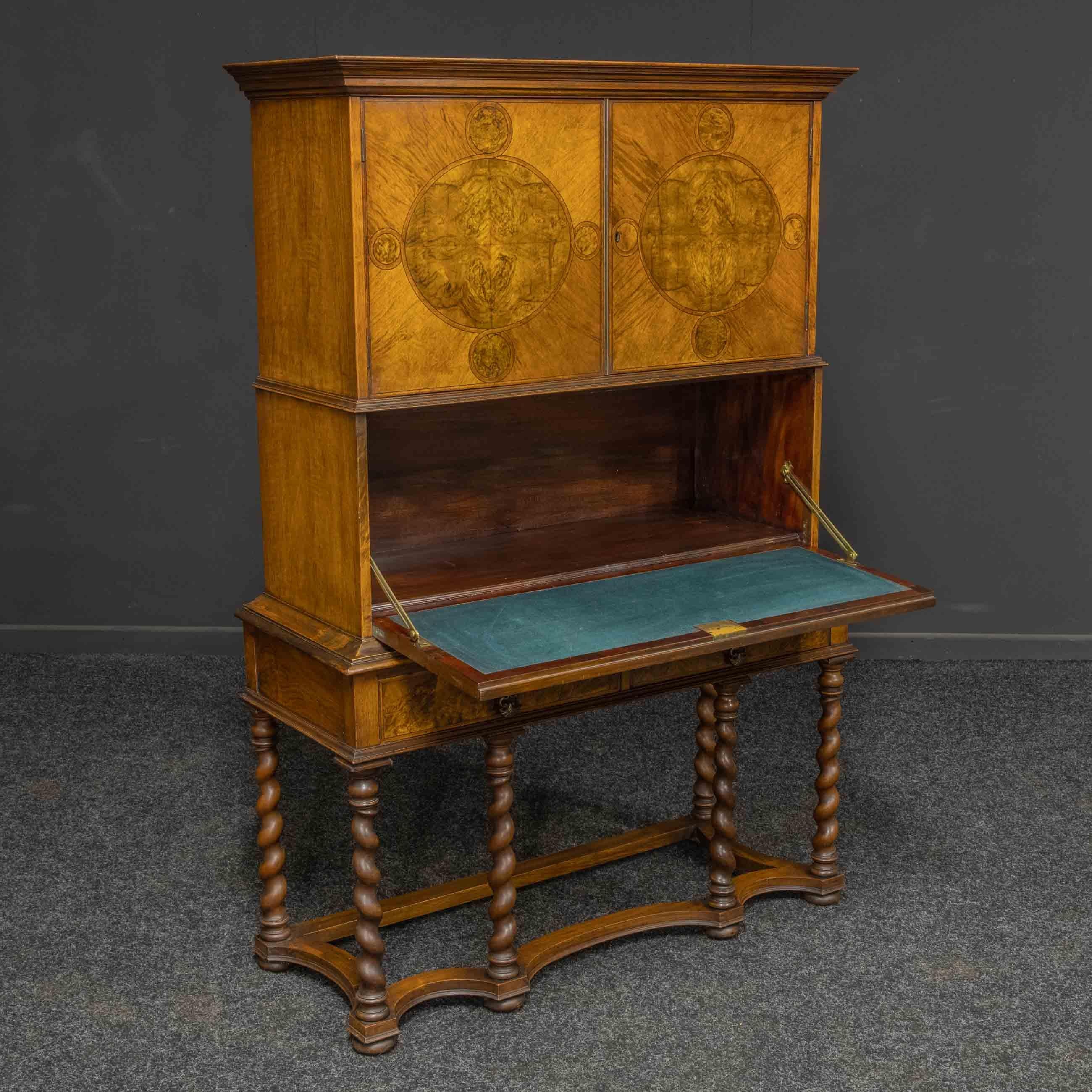 A superb early 20th Century decorative walnut veneered secretaire cabinet in the style of William and Mary. The stretchered base supports six barley twist legs that terminate on small bun feet above these are two mahogany lined drawers that have