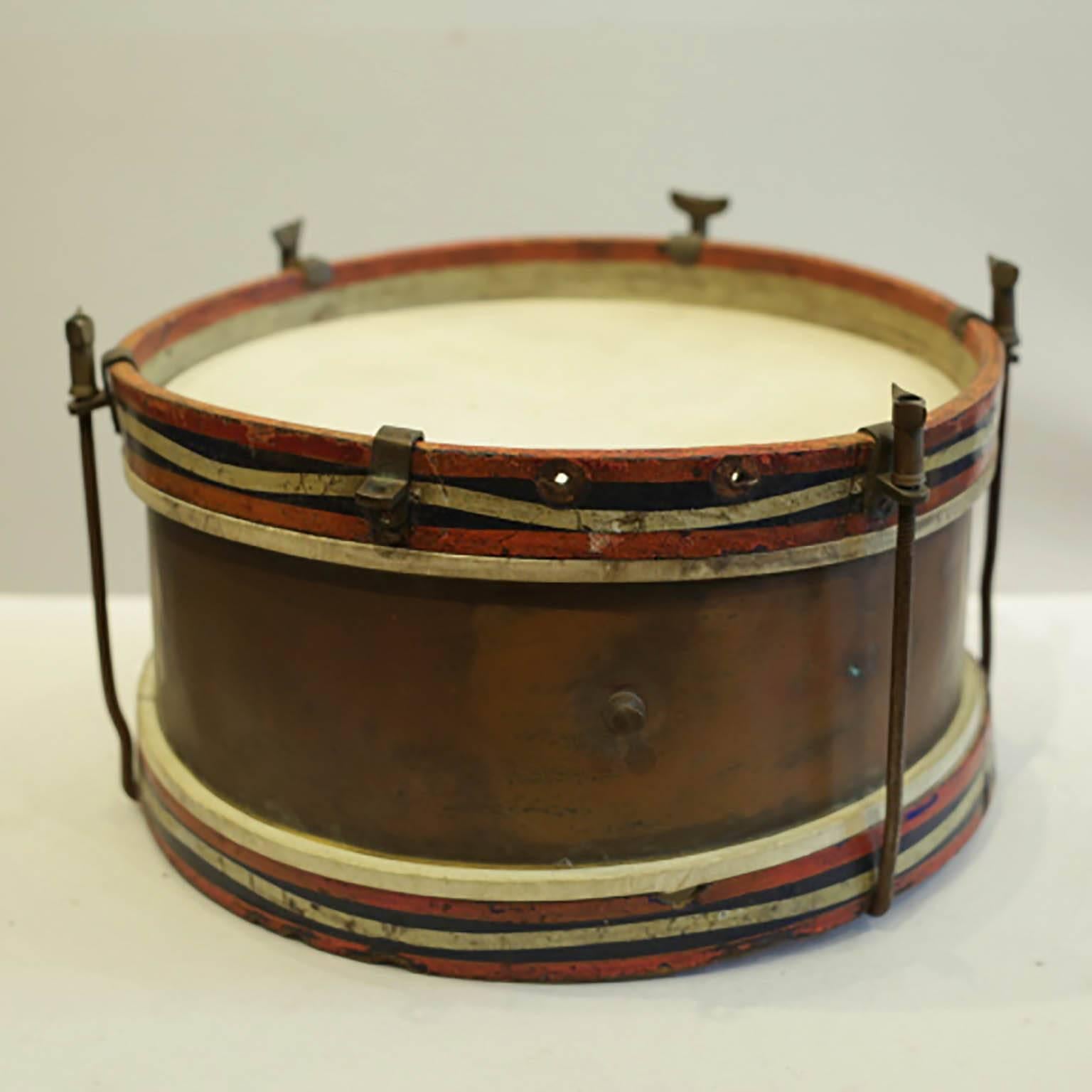 Vintage brass, wood and stretched calfskin snare drum. The calfskin has no cracks and is intact. The drum retains is original painted detailing on the sides. Possibly used in a marching band. The piece has retained its original finish and is in