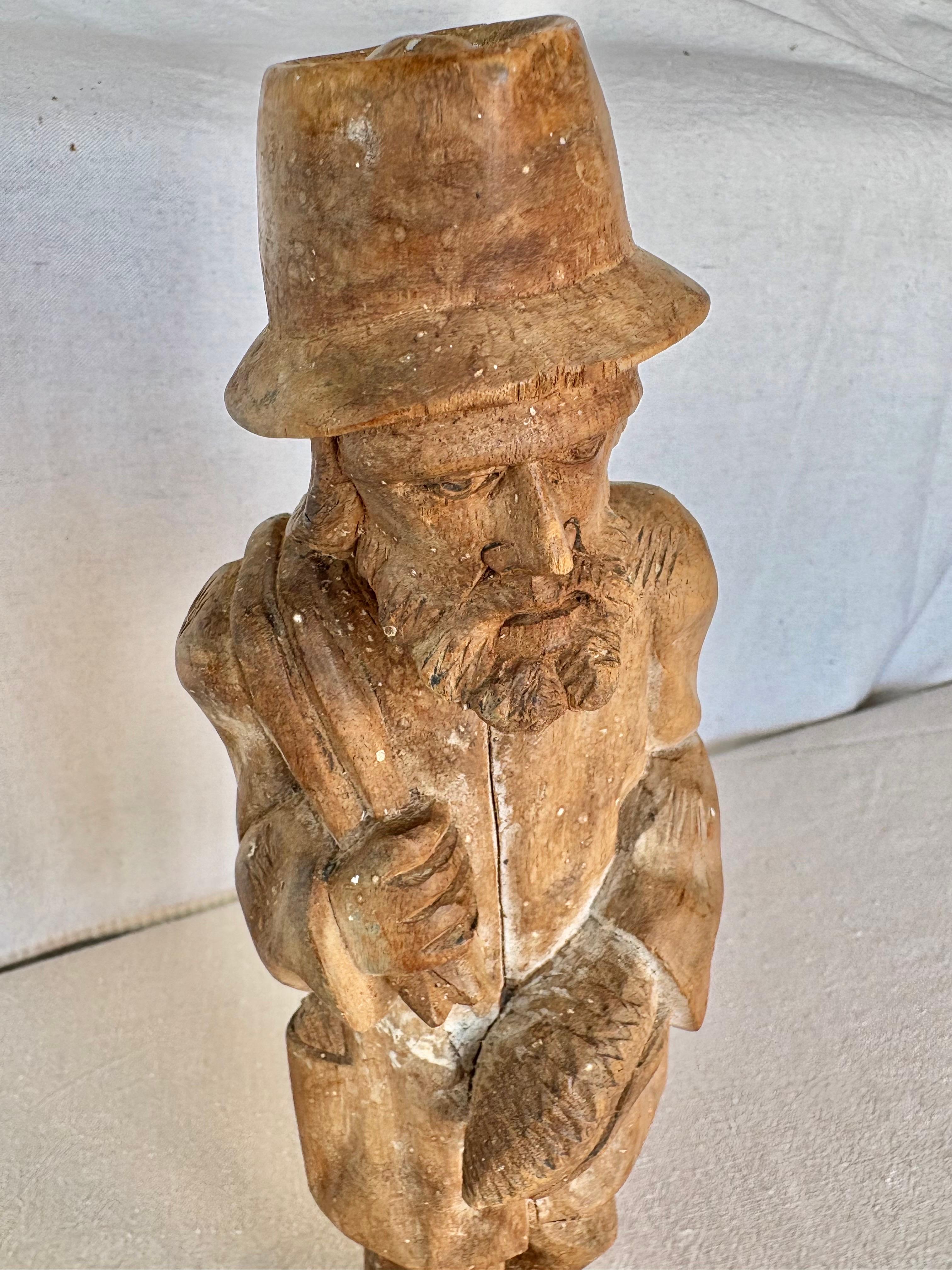 Diese handgeschnitzte Statue aus dem frühen 20. Jahrhundert wurde in den frühen 1900er Jahren aus Holz gefertigt und stellt einen Fischer dar. Das Stück ist aus einem massiven Stück Holz kunstvoll geschnitzt und zeigt einen Mann, der einen Fisch