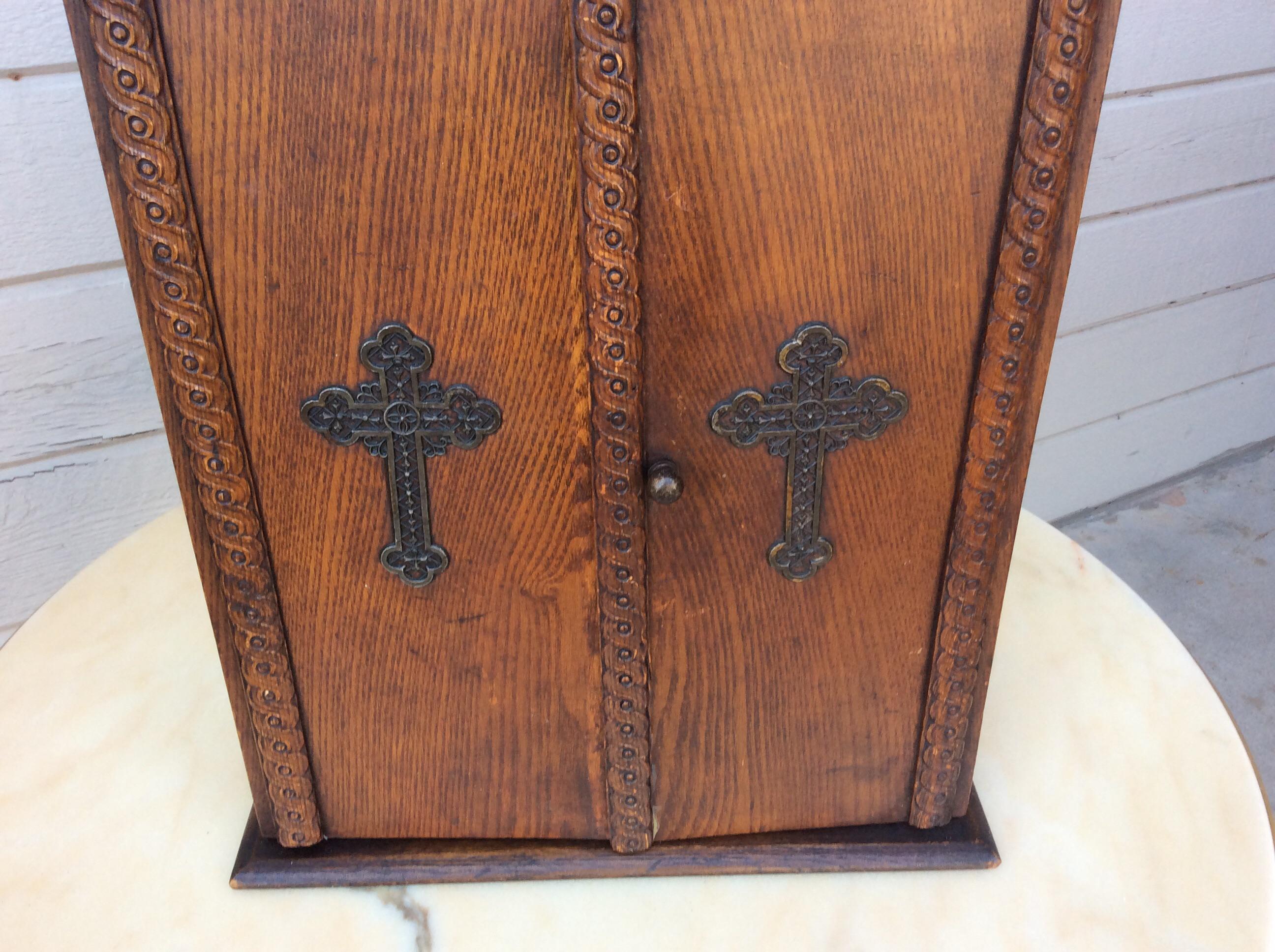 This Early 20th Century Wood Viaticum Cabinet and Home Altar Box is constructed with ornate details and two metal crosses on the front. This Alter Cabinet was once used for The Last Rites of the Catholic Church and contained the necessary articles