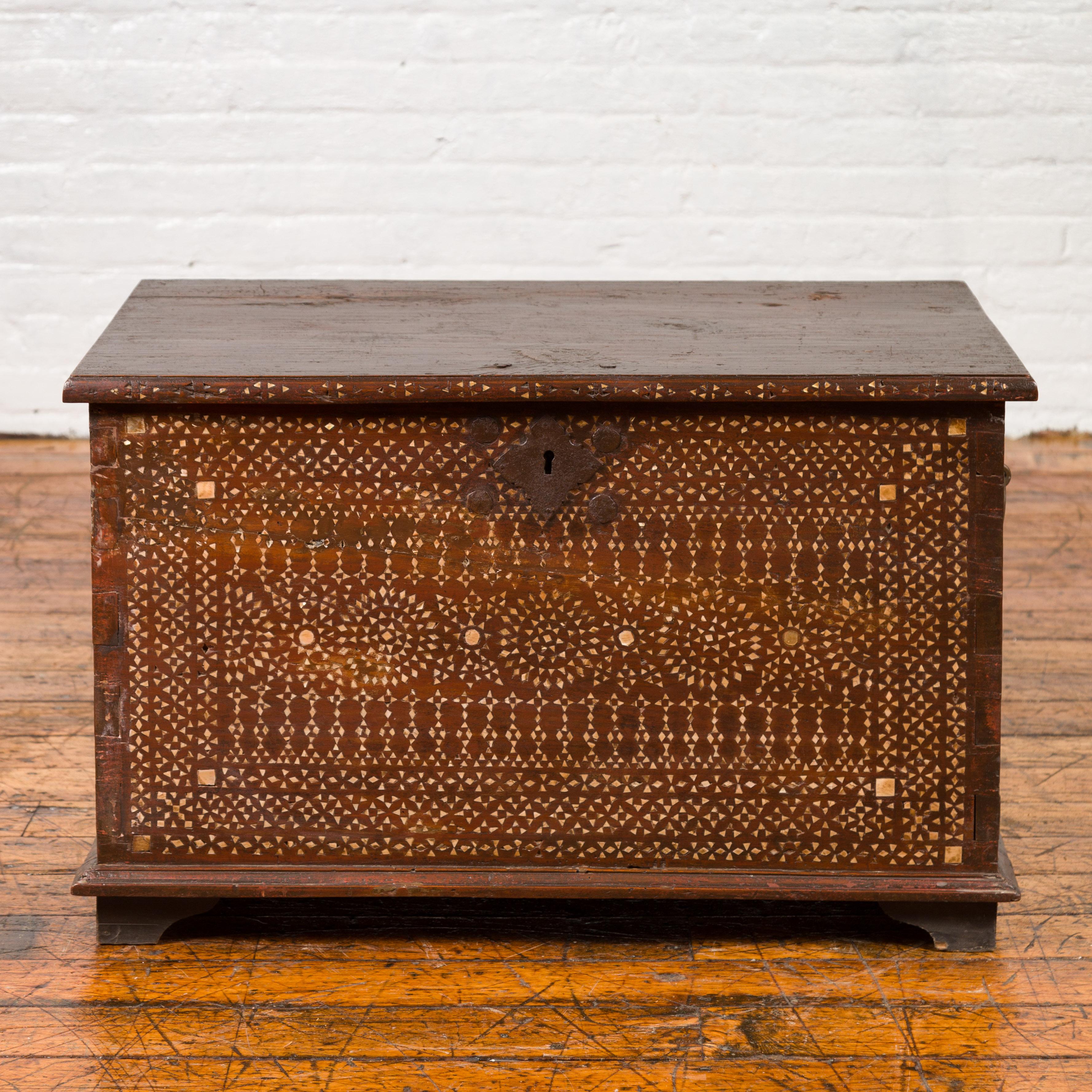 An antique Indonesian wooden blanket chest from the early 20th century, with mother of pearl inlay. Born in Jakarta during the early years of the 20th century, this blanket chest draws our attention with its rich geometrical decor created by lovely