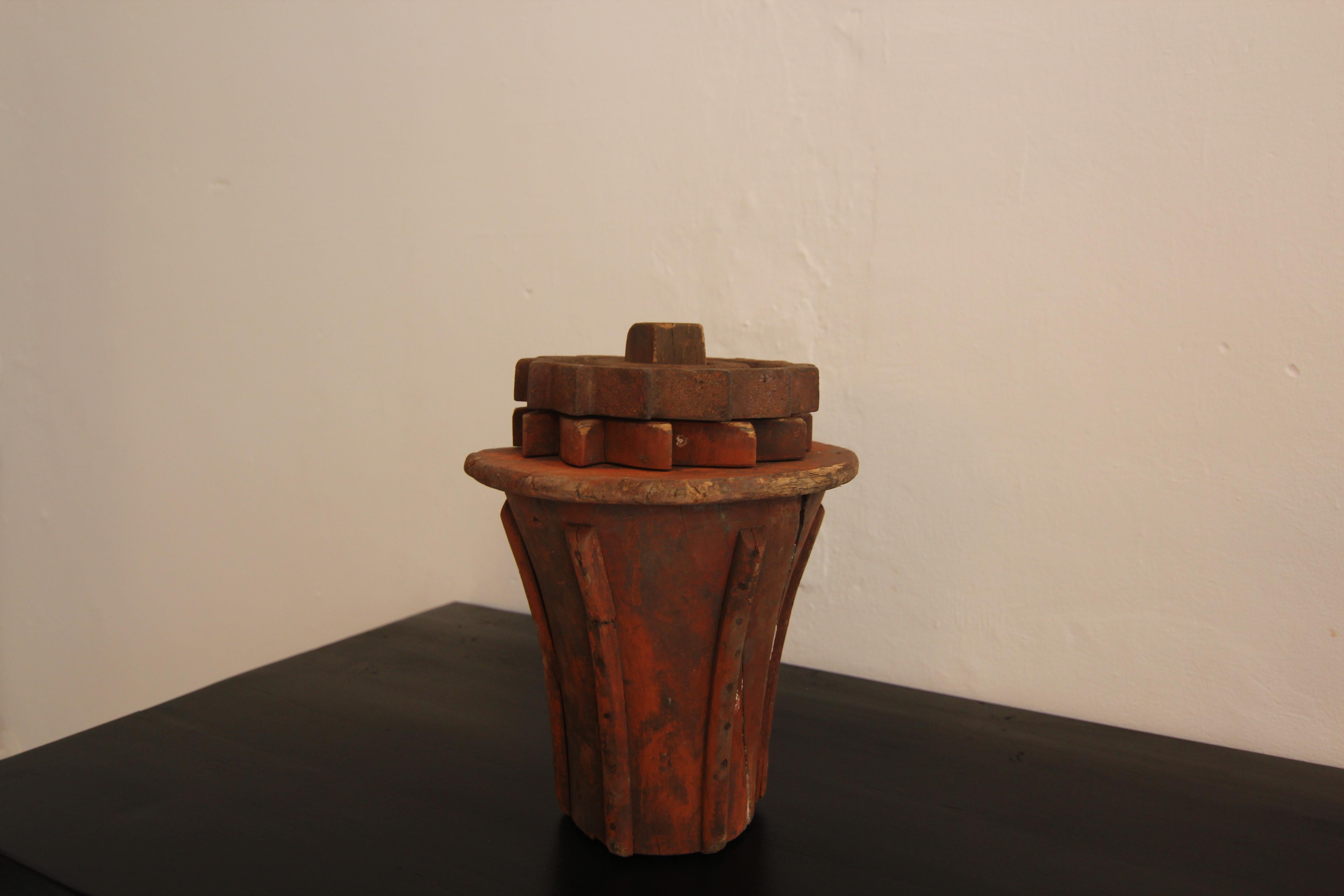 A early 20th century wooden casting pattern. Probably as part of a drive shaft.
Shaft in the shape of an inverted blunted cone with strips on the sides and a disc with a wooden gear wheel and an iron gear wheel on top. 

Very decorative abstract
