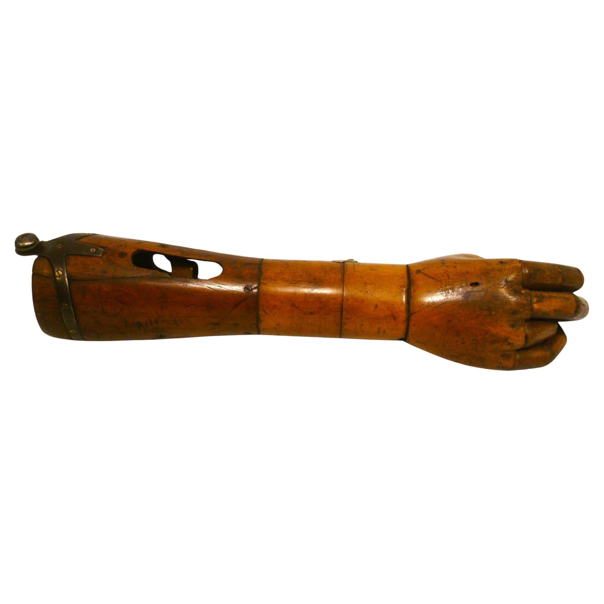 Il s'agit d'une initiative très précoce et  bras prothétique. Il semble qu'il ait été fabriqué en Angleterre, mais je n'en suis pas sûr. 
La main sculptée en bois est articulée, réaliste et très bien réalisée. C'est la technologie du début du 20e