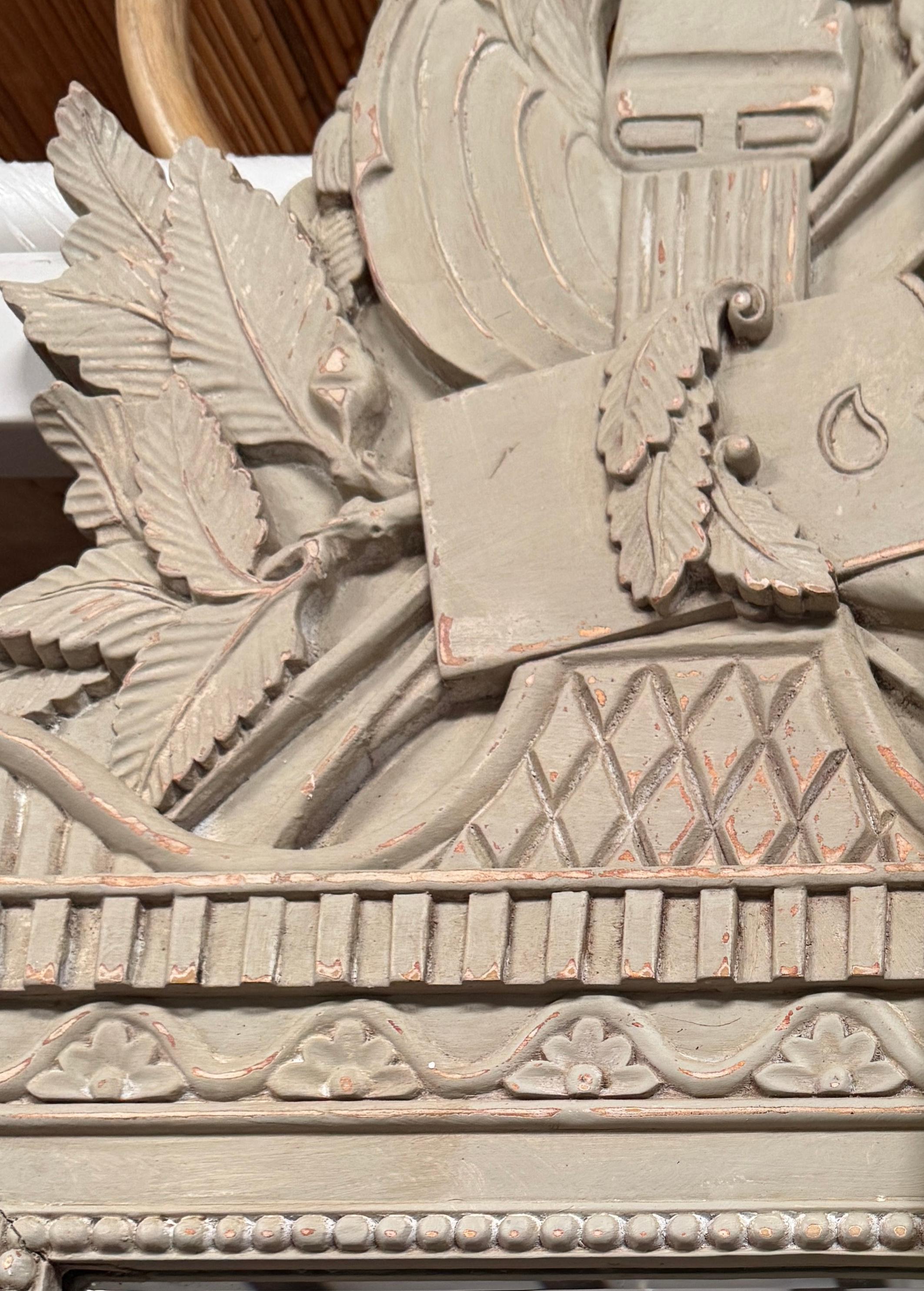 Bellissimo specchio Trophy in legno dei primi del Novecento con tema la caccia.  Lo specchio è rifinito con una vernice color tortora e presenta una bella patina. La parte superiore o corona dello specchio contiene frecce, foglie e un'ascia