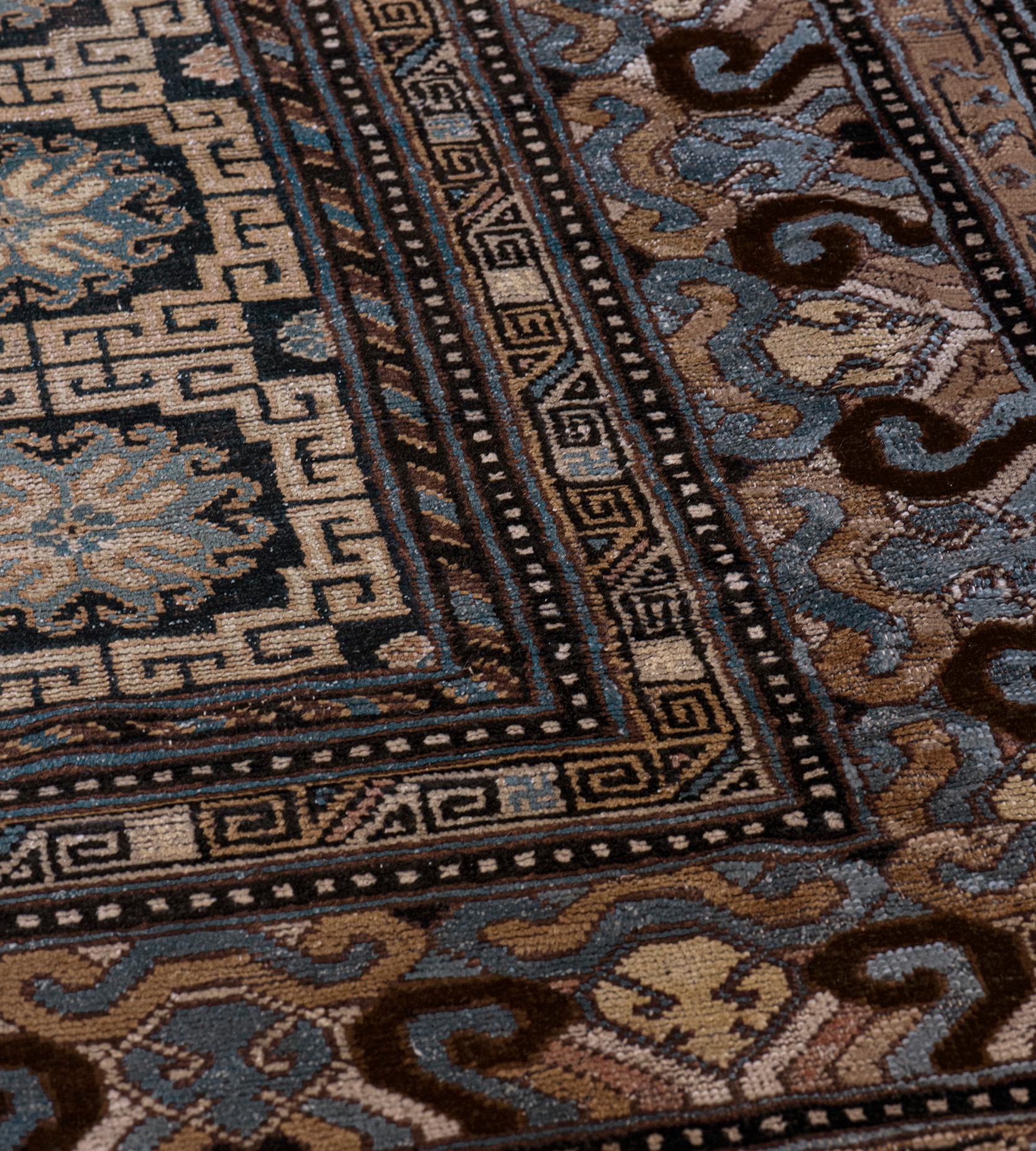 This traditional handwoven Samarkand Khotan rug has a field with five vertical rows of eight indigo and ivory square stepped panels containing rosettes divided by small rosette panels linked by a hooked vine, in an indigo, light brown and ivory