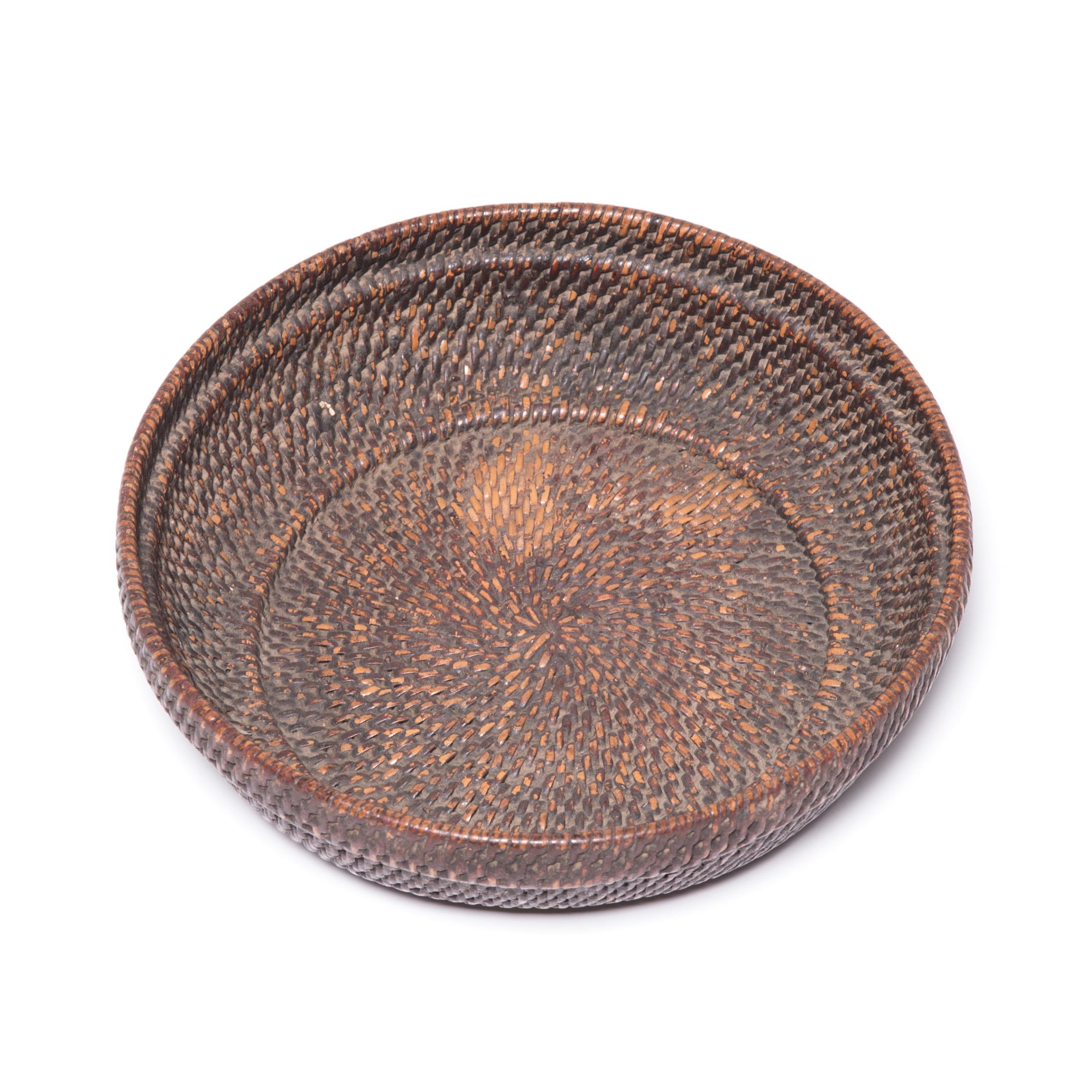 Tightly woven of natural reeds, this neat basket likely contained offerings of food, money and fruits presented as part of ritual ancestor worship on a family altar. Over the course of the past century, the original deep brown has worn just where