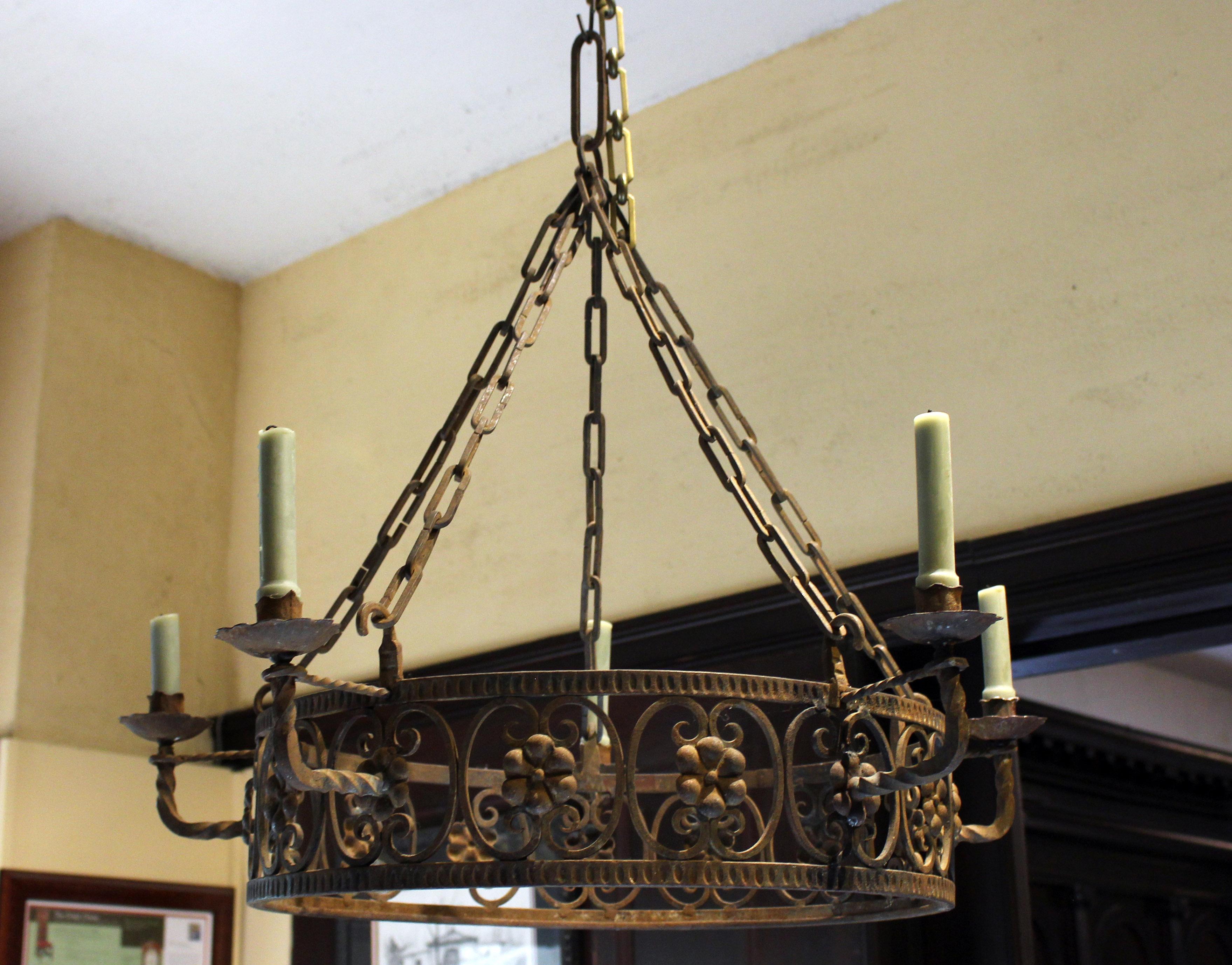 Early 20th century wrought iron 5-candle chandelier, French or Italian. Never electrified. Floral cast brosses entwined in reverse c-scrolls. Provenance: Estate of Katharine Reid, Cleveland Art Museum former director, purchased from Summerland, CA