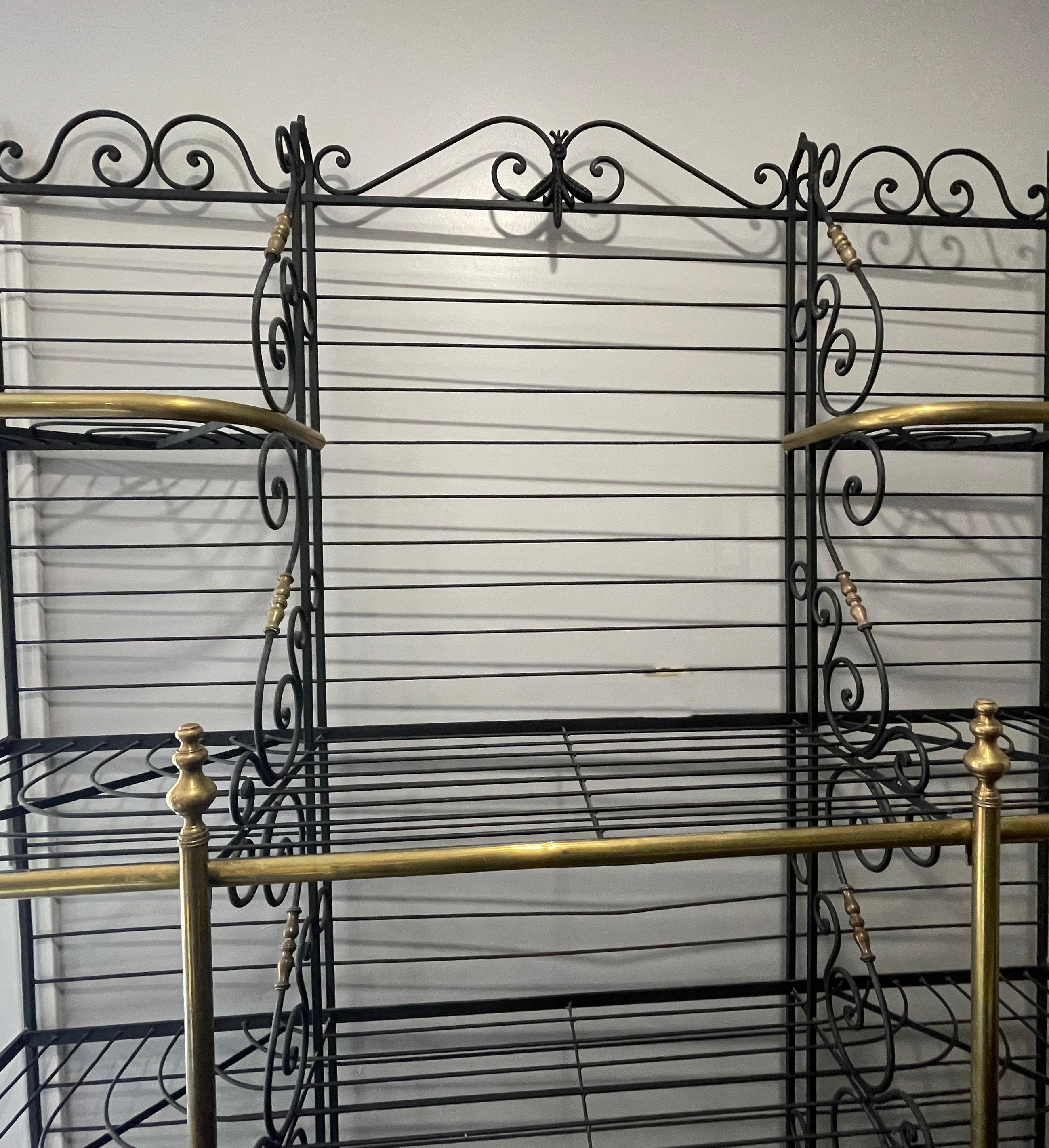 Crafted circa 1930, the wide shelf made primarily of iron, features decorative brass columns and edging shelf trim, bronze mounts and embellished with a wheat motif at the pediment. The display rack has four tiers of shelving including split