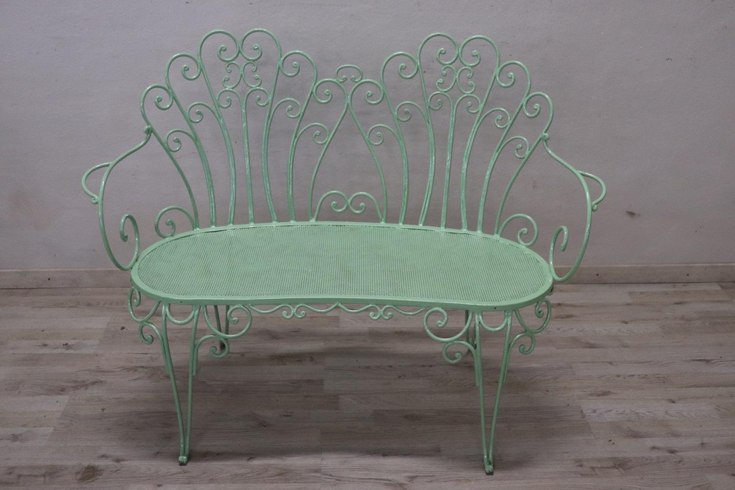 Beautiful refined garden set in circa 1930s. Two chairs, one settee and a round wrought iron table. Refined iron decoration with curls and swirls. The iron has been lacquered in a lovely light green shade. This garden set is perfect for embellishing