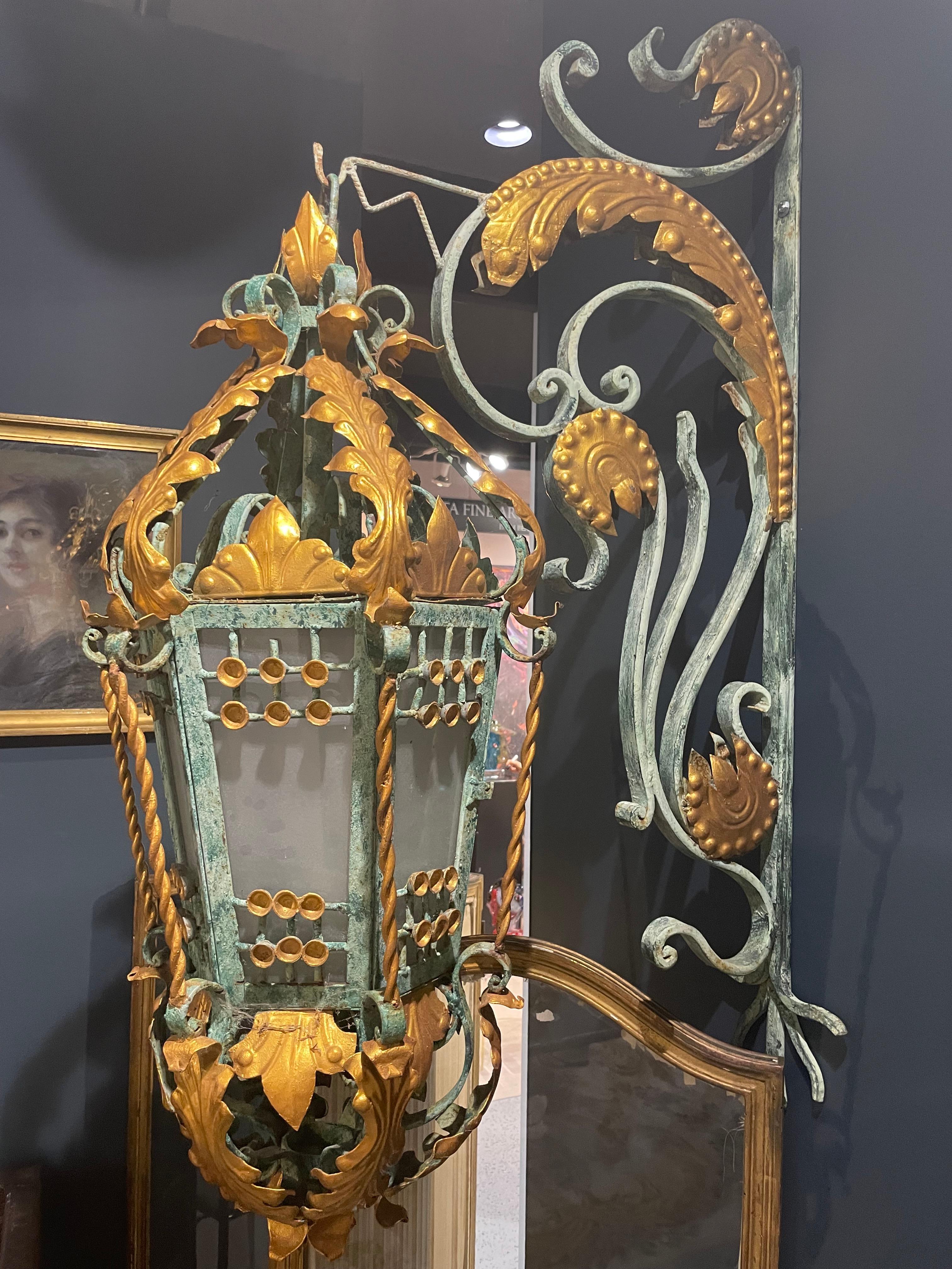 Monumental wrought iron outdoor Lantern suspended by a coat hook. These majestic lanterns are most decorative. 9 are available!
The work of wrought iron is delicate with its golden acanthus leaves; the tops of the lanterns are like royal crowns,