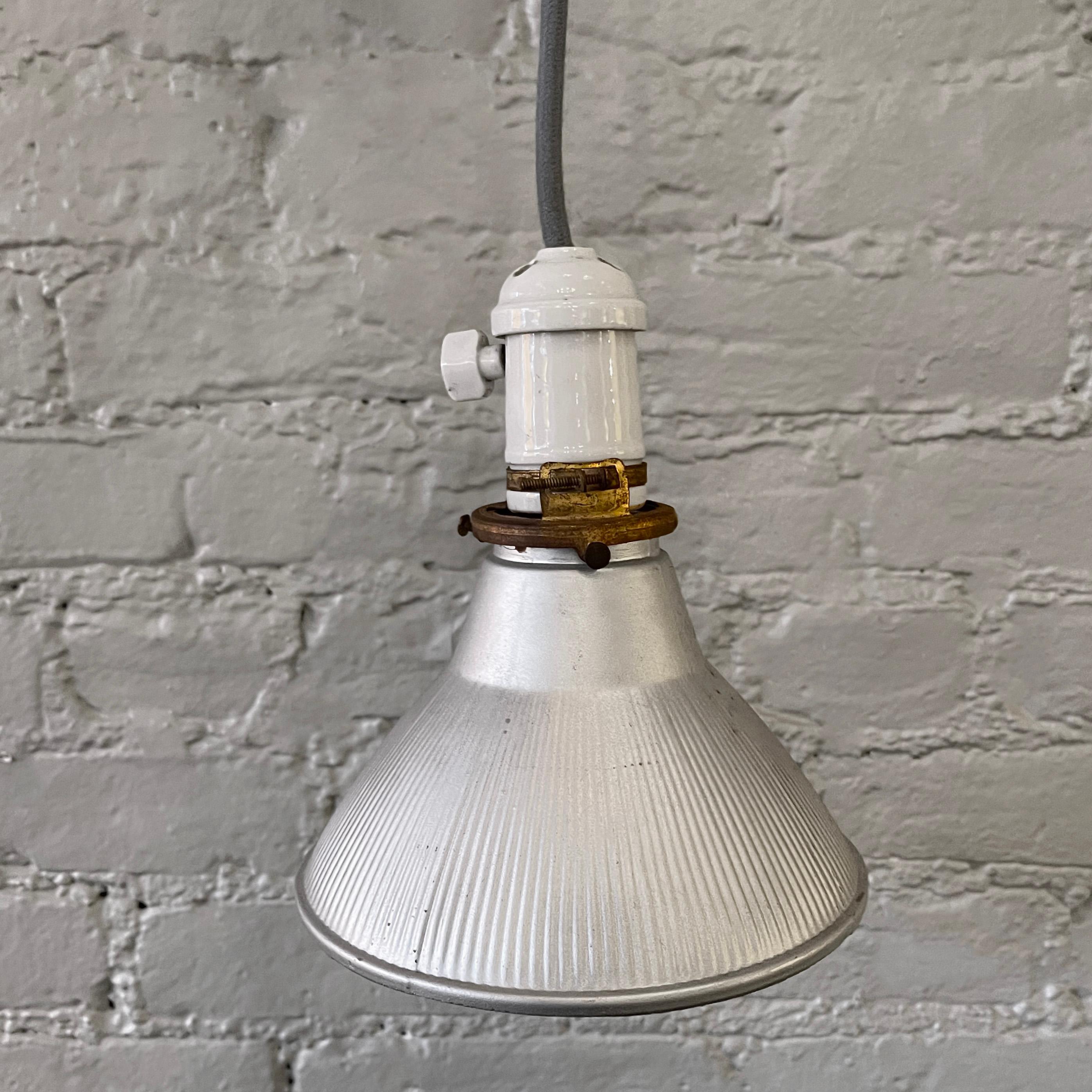 Early 20th century, X-Ray mercury glass bell pendant light features a matte silver exterior with reflective silver interior on a porcelain socket with brass fittings is newly wired with 36 inches of blue cord with matching porcelain canopy.