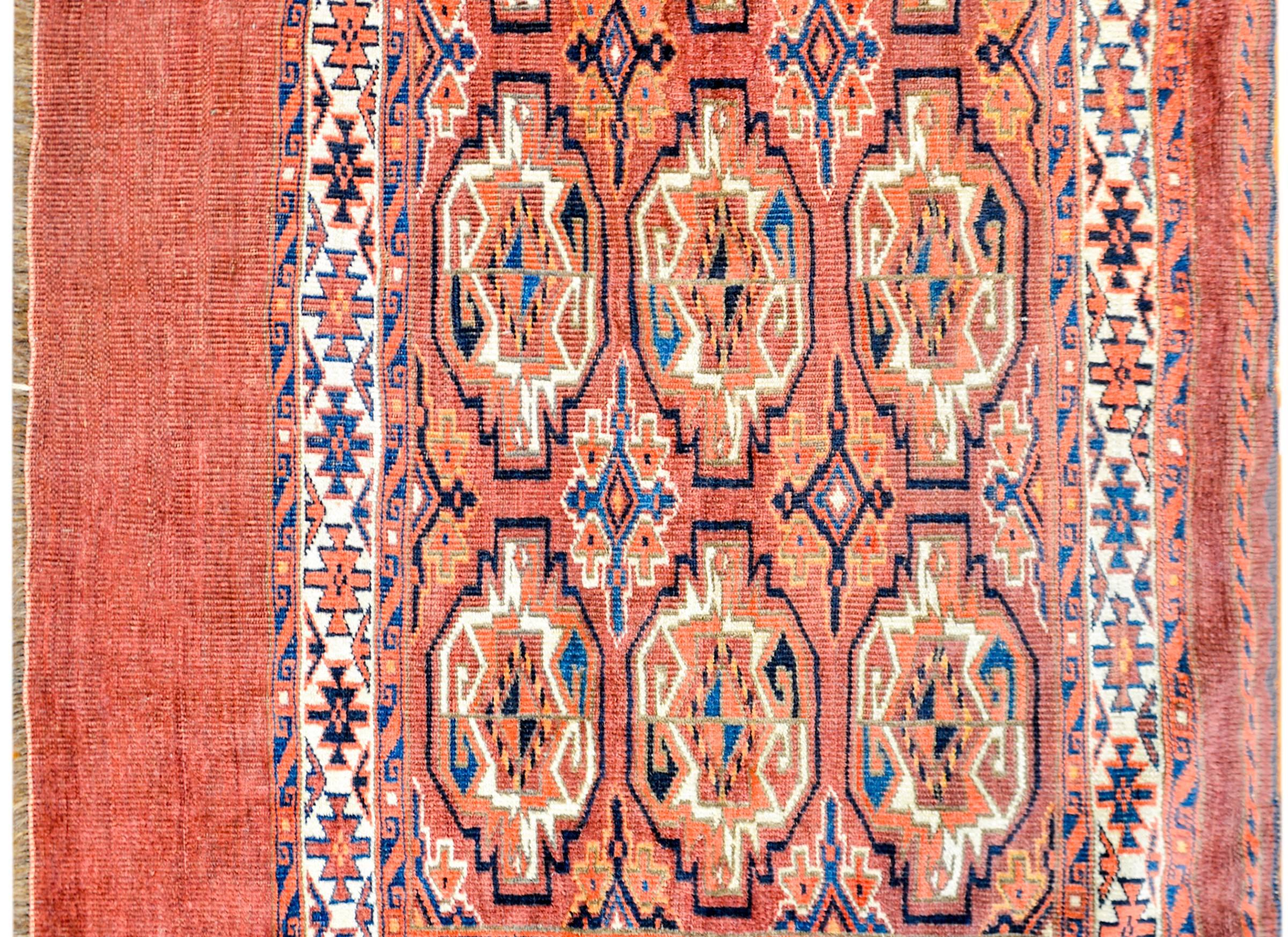 Ein persischer Yamut-Taschenteppich aus dem frühen 20. Jahrhundert mit schönen geometrischen Medaillons in Indigo, Karmesinrot und natürlicher Wolle auf einem blasskarmesinroten Hintergrund, umgeben von einer komplementären geometrischen Bordüre.