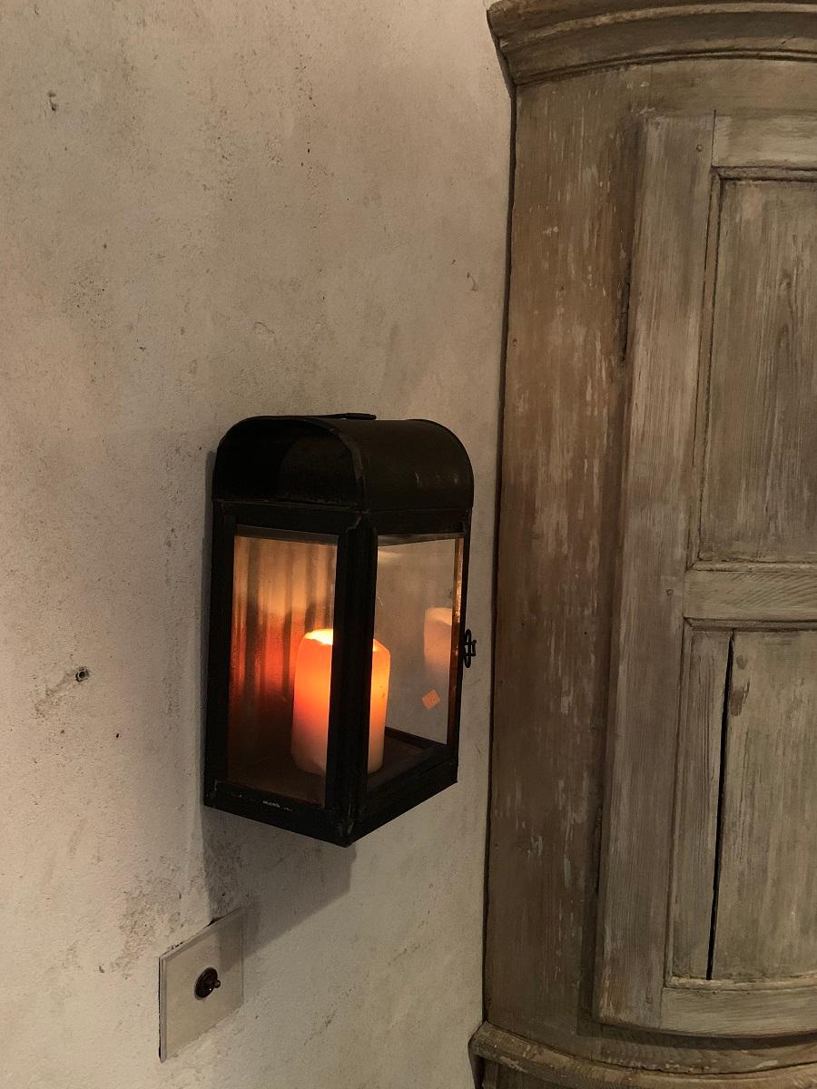 A early 20th century iron wall lantern with hand blown glass windows and a hinging sidedoor. Originally for petroleum, now fitted for candles.