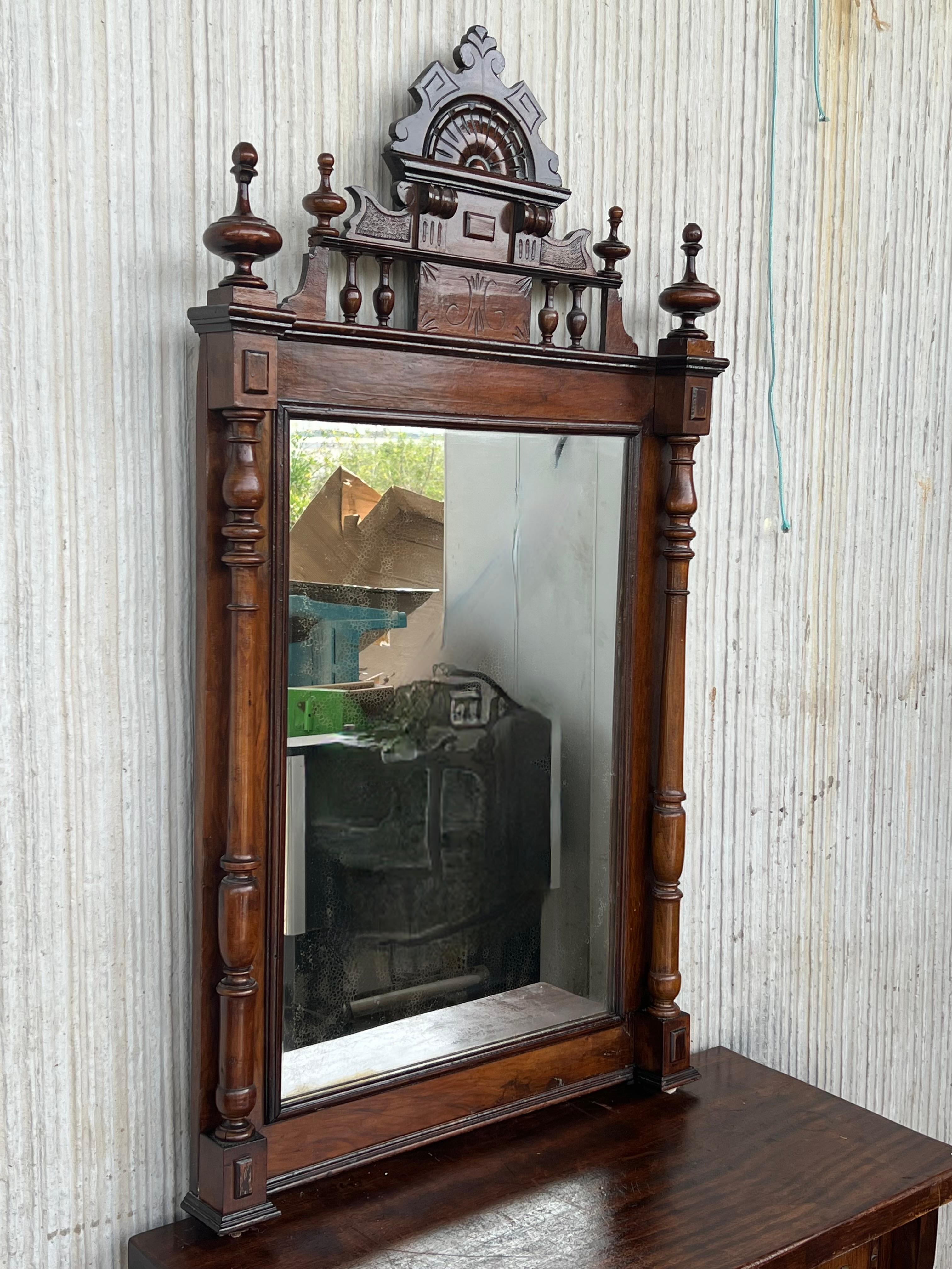 Early 20th French ebonized mirror with turned columns and high carved details.