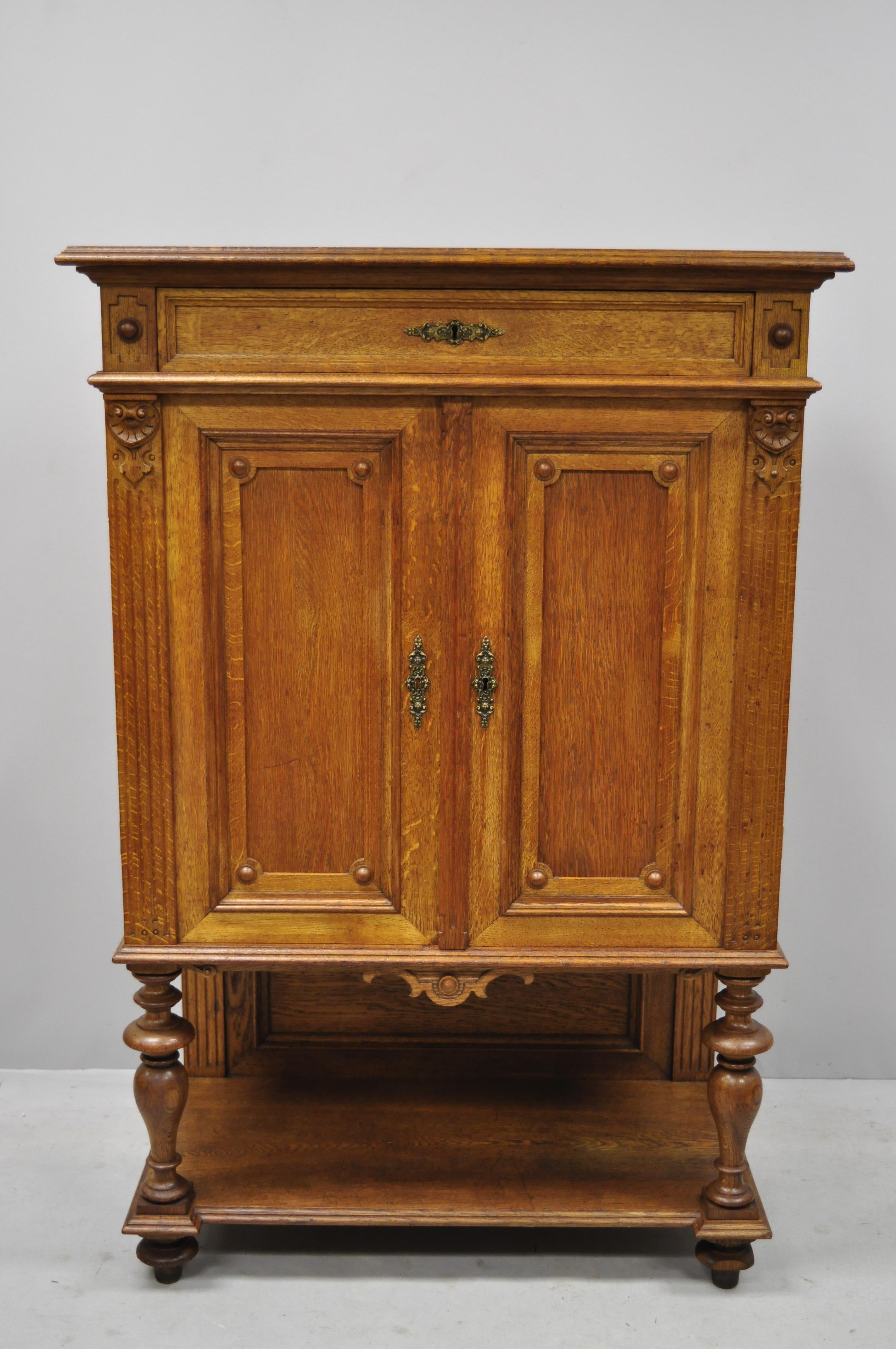 Early 20th French Renaissance style golden oakwood small cupboard China cabinet. Item features solid wood construction, beautiful wood grain, nicely carved details, 2 swing doors, 10 dovetailed drawers, 2 adjustable shelves, solid brass hardware,