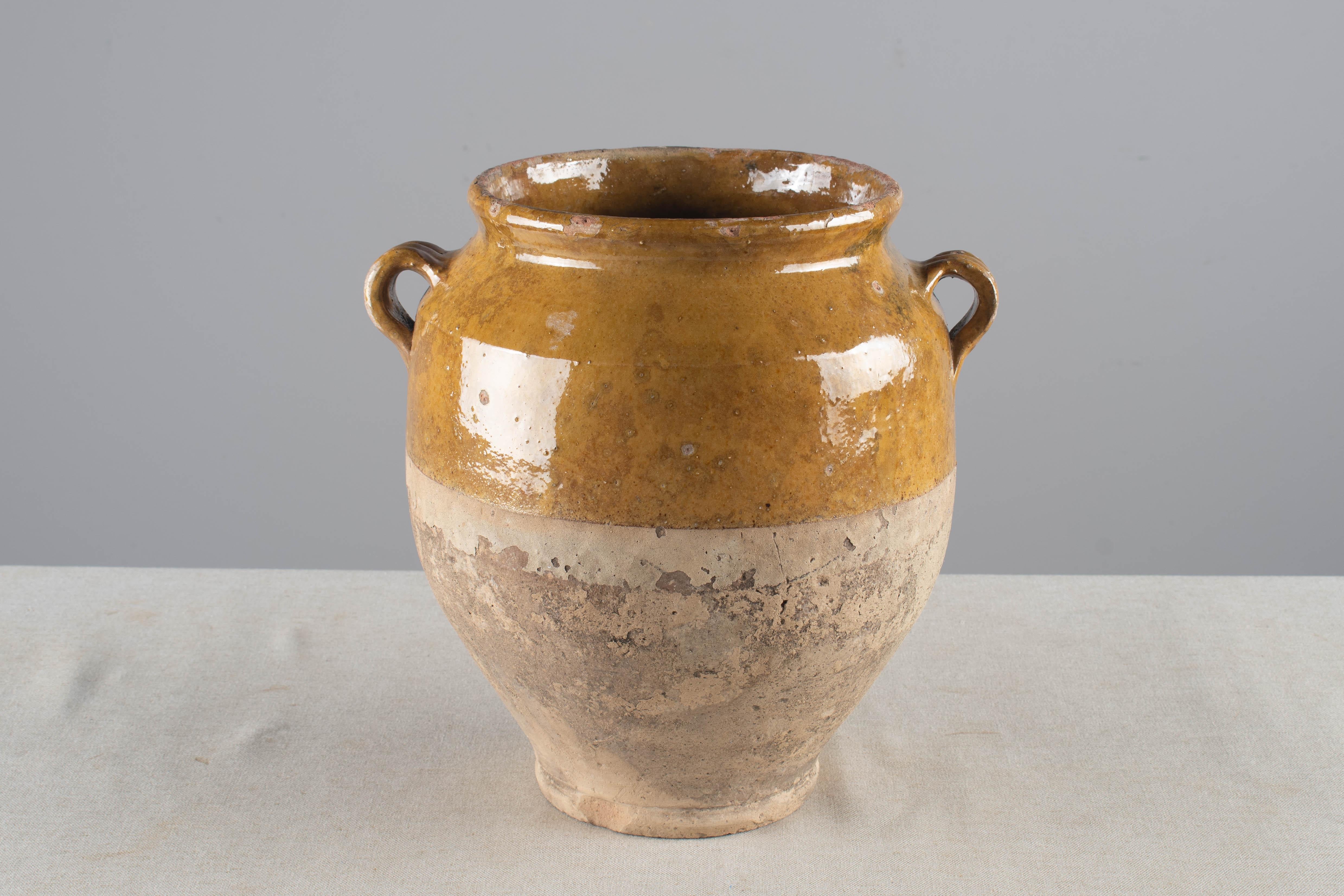 An early 20th earthenware confit pot from the Southwest of France with traditional yellow ochre glaze. Chips and losses to glaze, NO hairline. These ordinary earthenware vessels were once used daily in the French country home and have beautiful