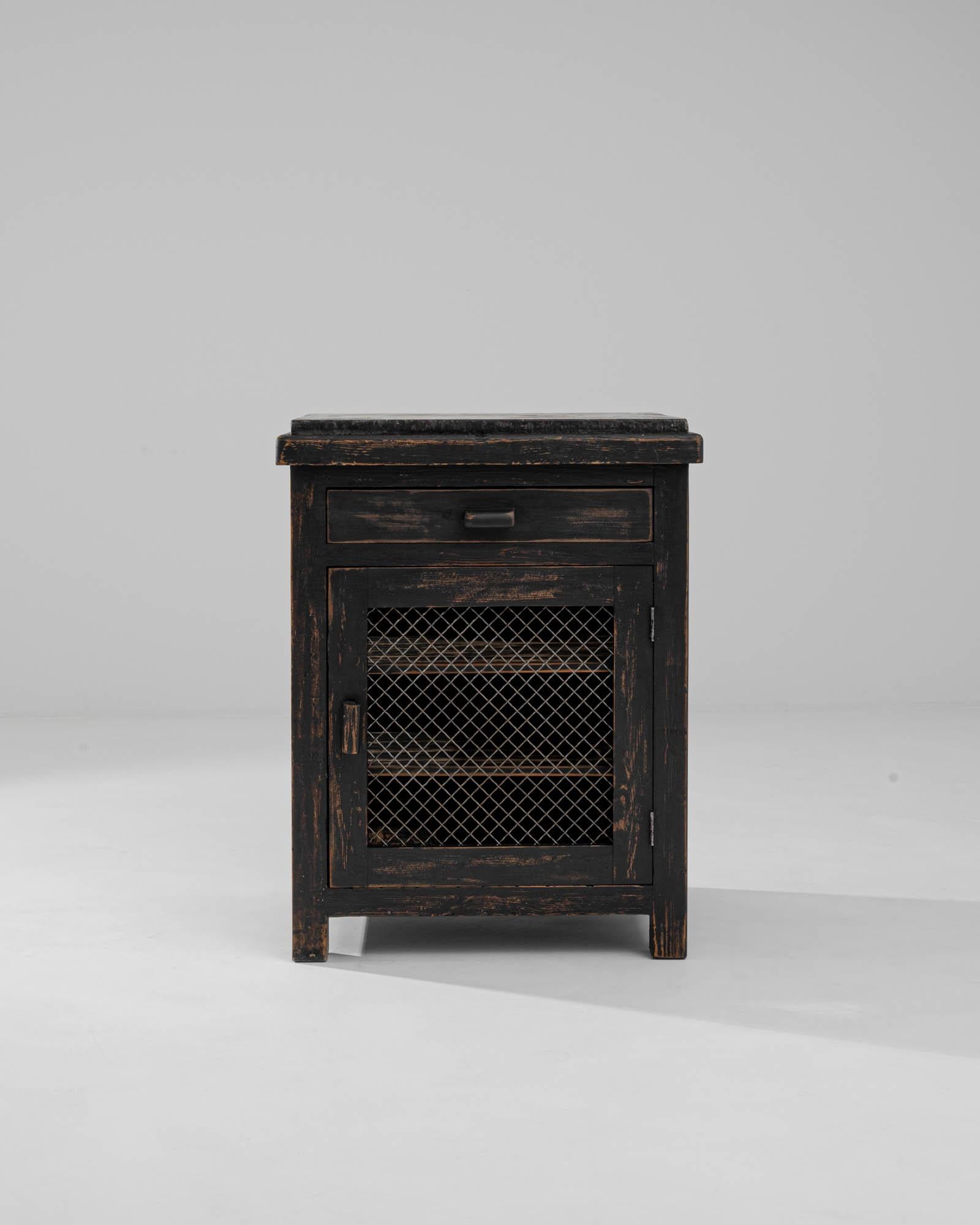A black stone tabletop adds an elegant crowning touch to this vintage Provincial cabinet. Built in France in the early 20th century, this piece would have originally been used as a larder; the metal mesh of the door and sides would have allowed air