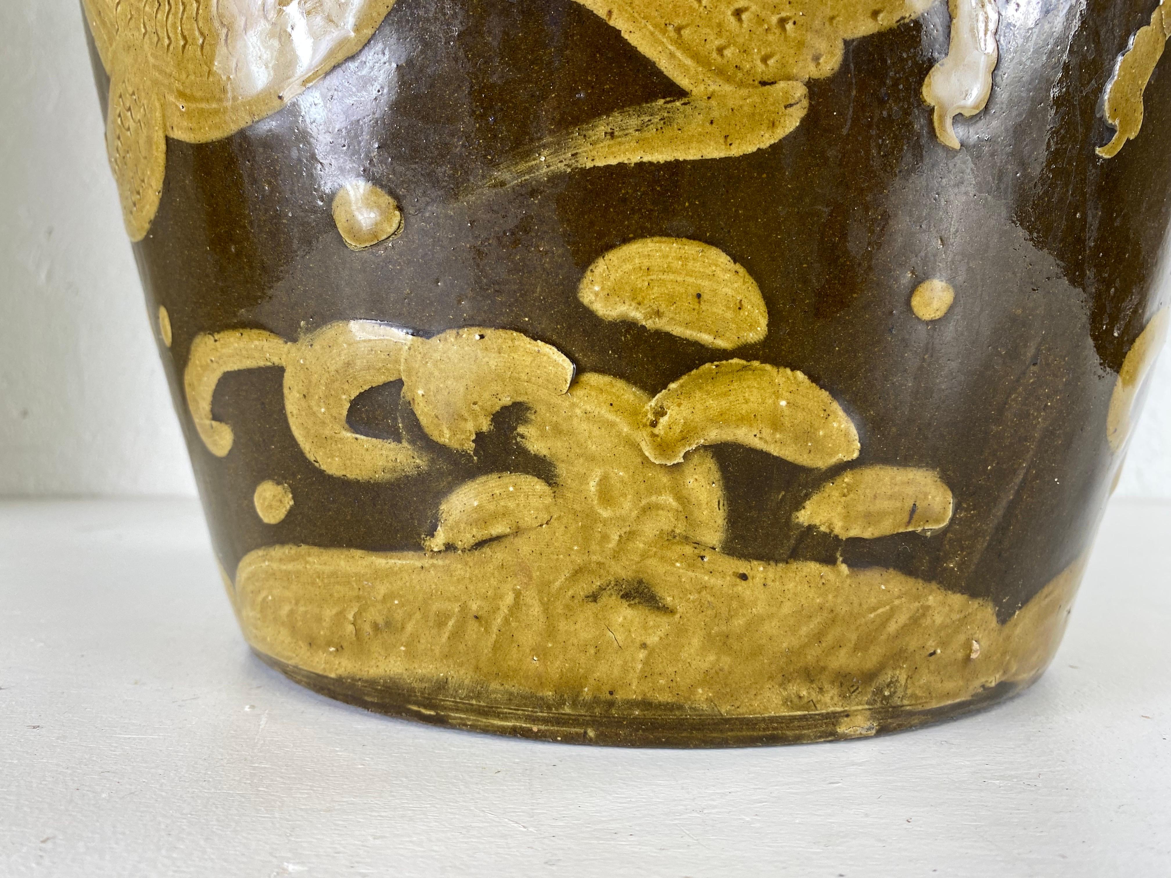 This is a hand mid-century Chinese export hand painted terra-cotta garden stool. This garden stool has a dark brown background with a golden Amber hand painted dragon decoration around the entire surface of the piece. The top has a Greek key border