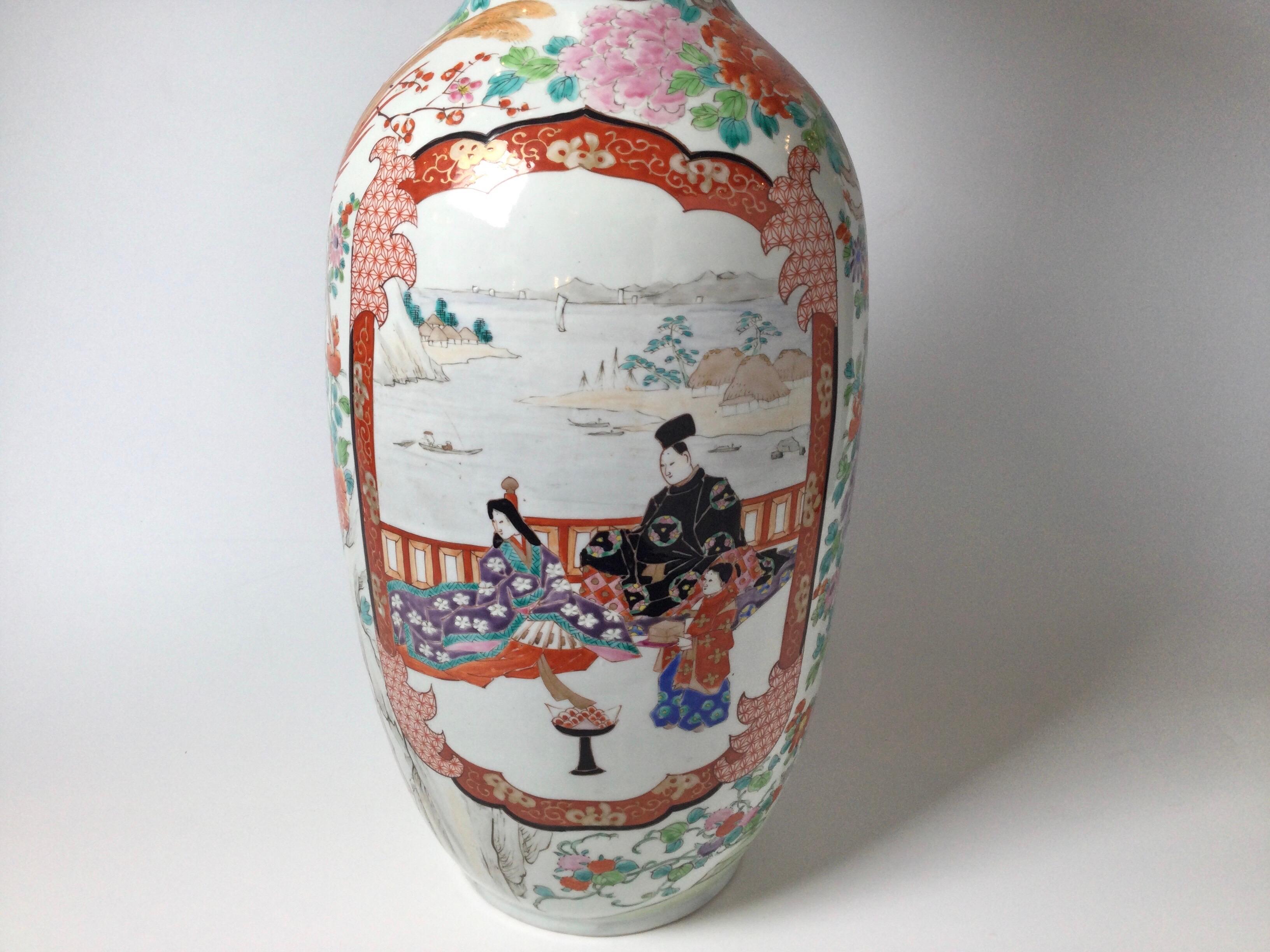 Elegant hand painted Japanese porcelain Kutani Vase, 25.5 inches tall with delicate and crisp hand painted Japanese scenes with the classic iron red accent color. The front cartouches with aristocratic people, with the sides of beautifully painted