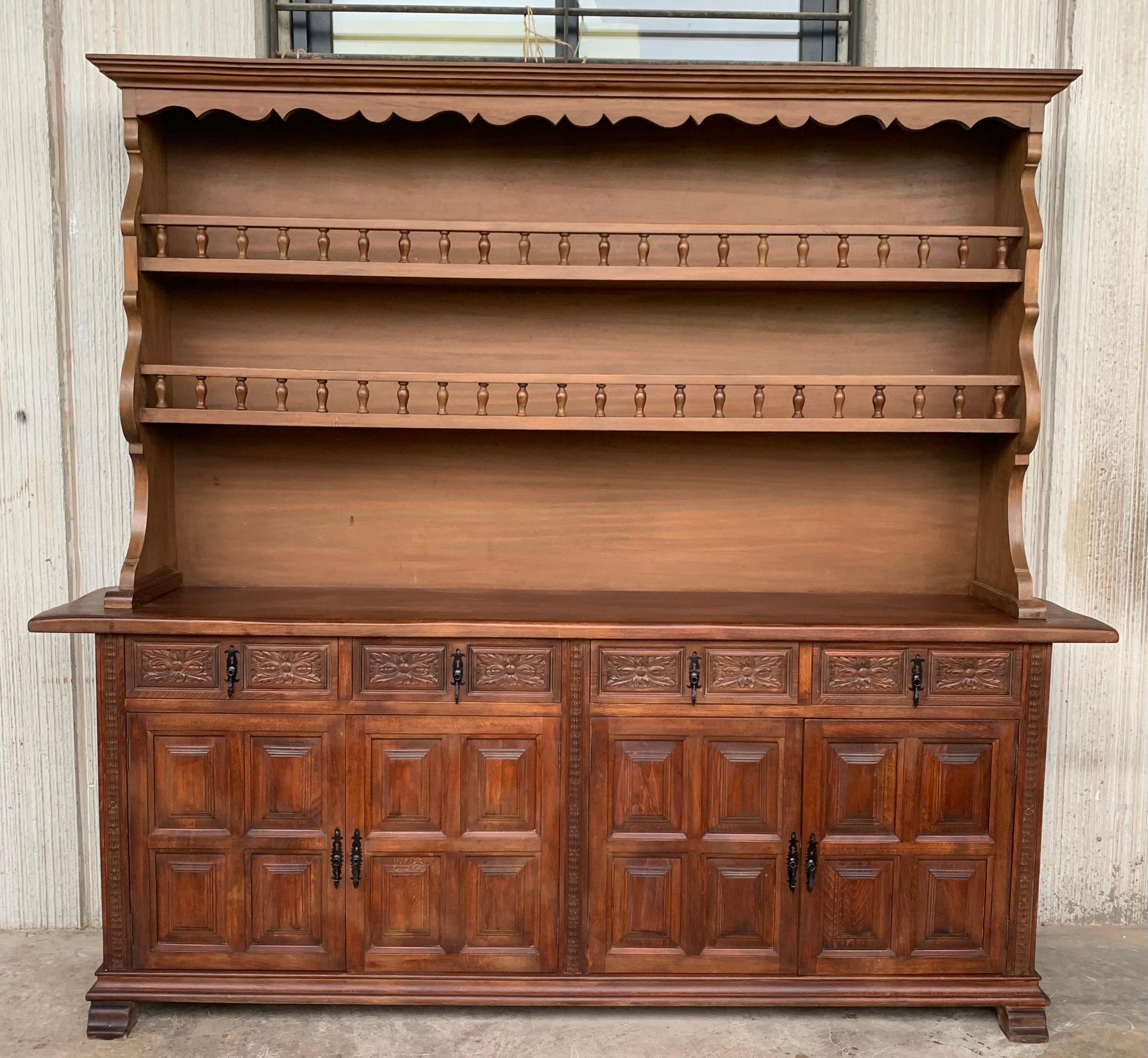 From Northern Spain, constructed of solid pine, the rectangular top with molded edge atop a conforming case housing four drawers over four doors, the doors paneled with solid walnut, raised on a plinth base. The drawers are hand carved and the edges