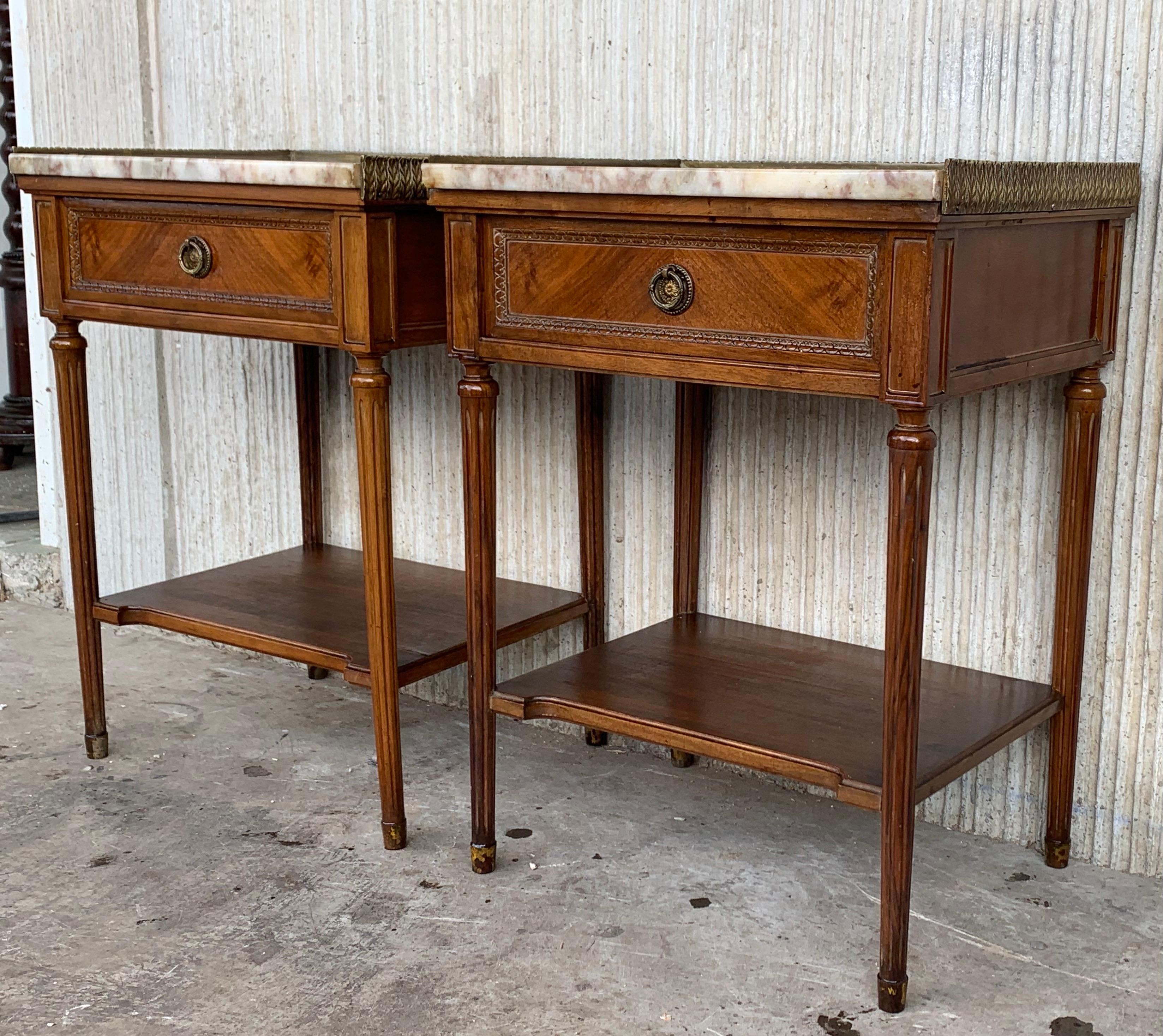 Early 20th century pair of nightstands with one-drawer and bronze bordering marble top.