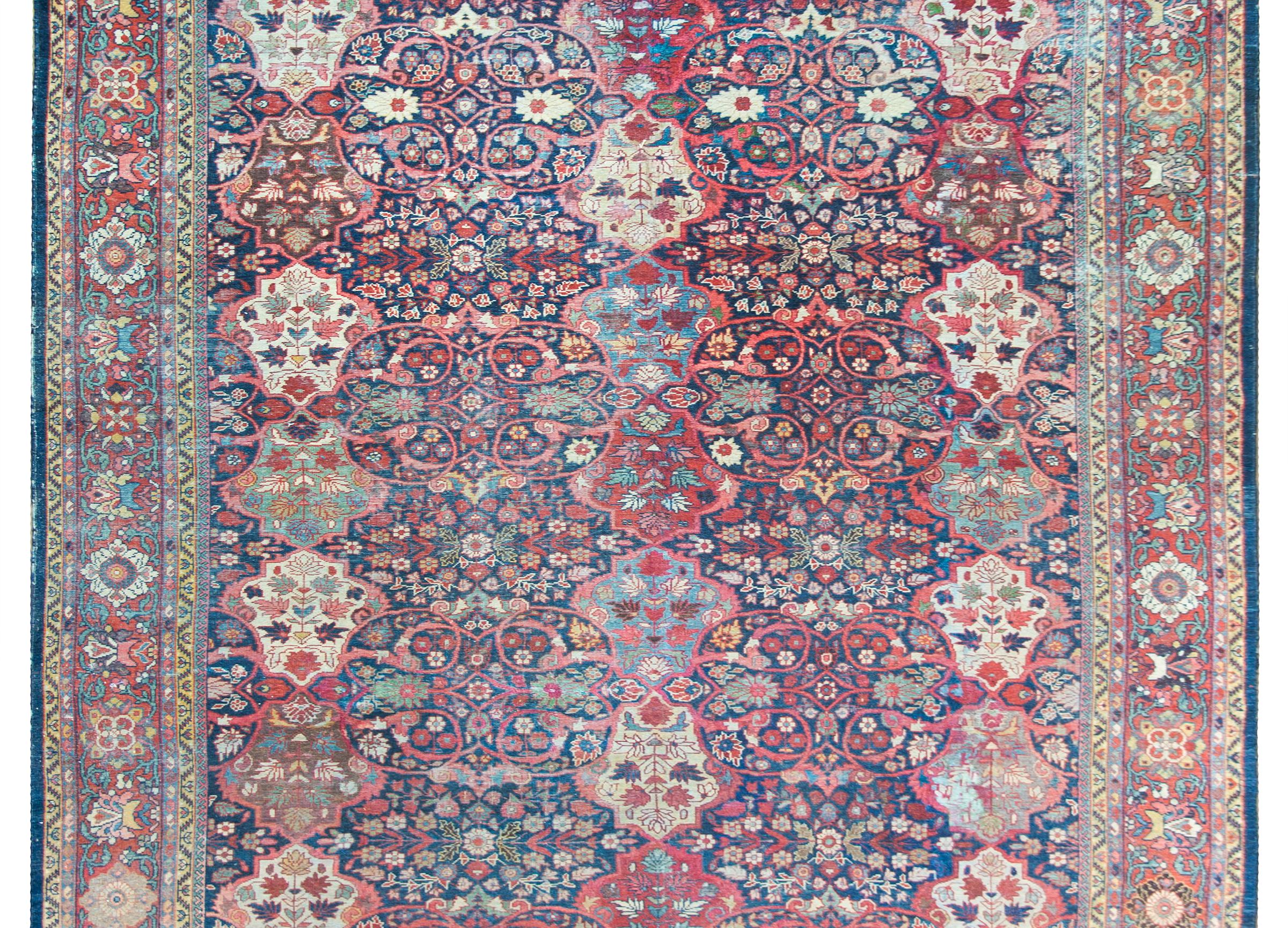 A gorgeous early 20th century Persian Mahal rug with the most wonderful floral pattern containing myriad large floral medallions living amidst a field of more stylized flowers and scrolling vines, woven in crimson teal, pink, white, indigo, and