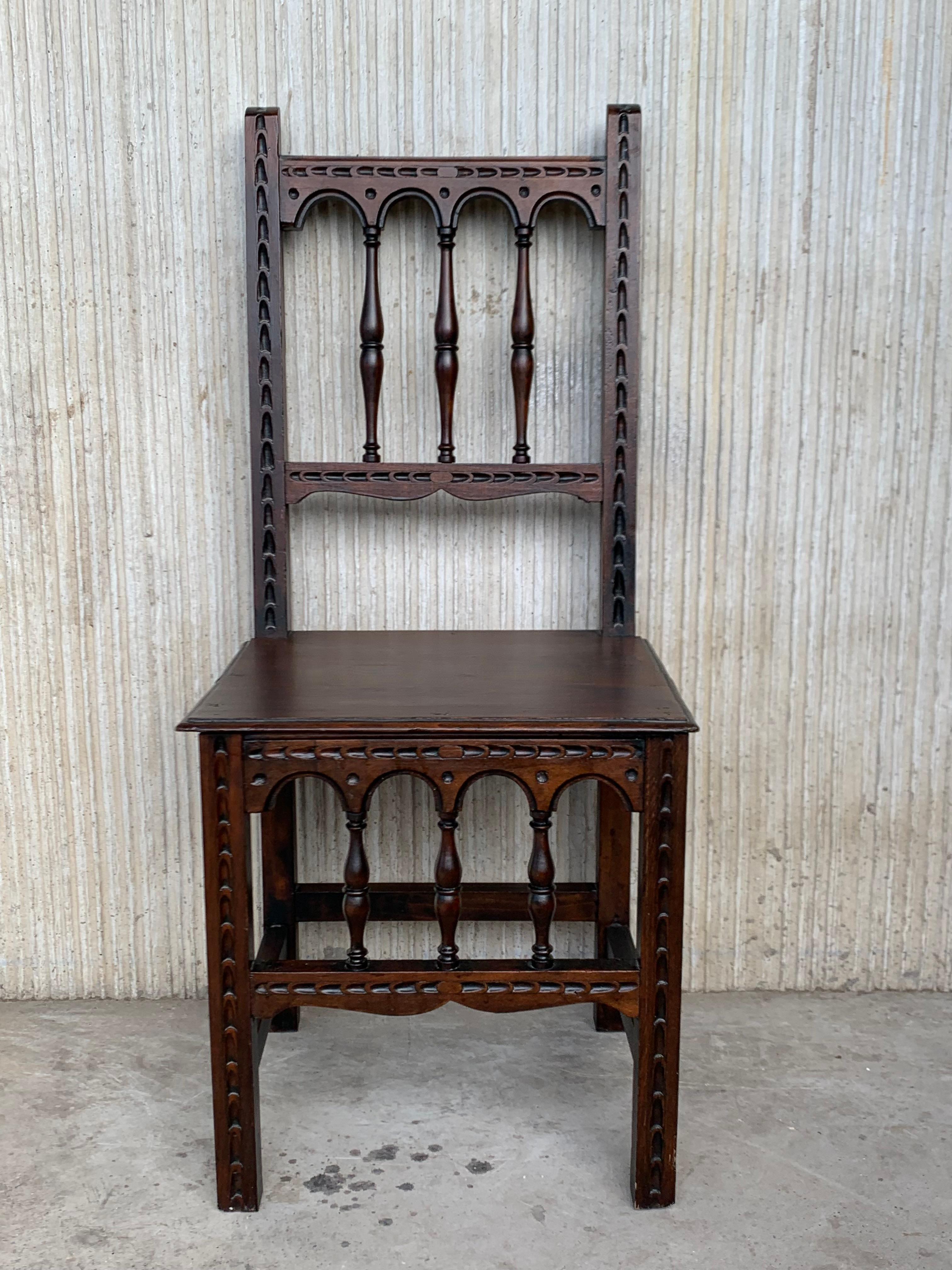 A set of 4 Spanish chairs with wood seat on walnut and sycamore frames with hand carved decoration. These chairs are true to the Spanish character and each features carvings that employ typical Spanish elements. 
  
  