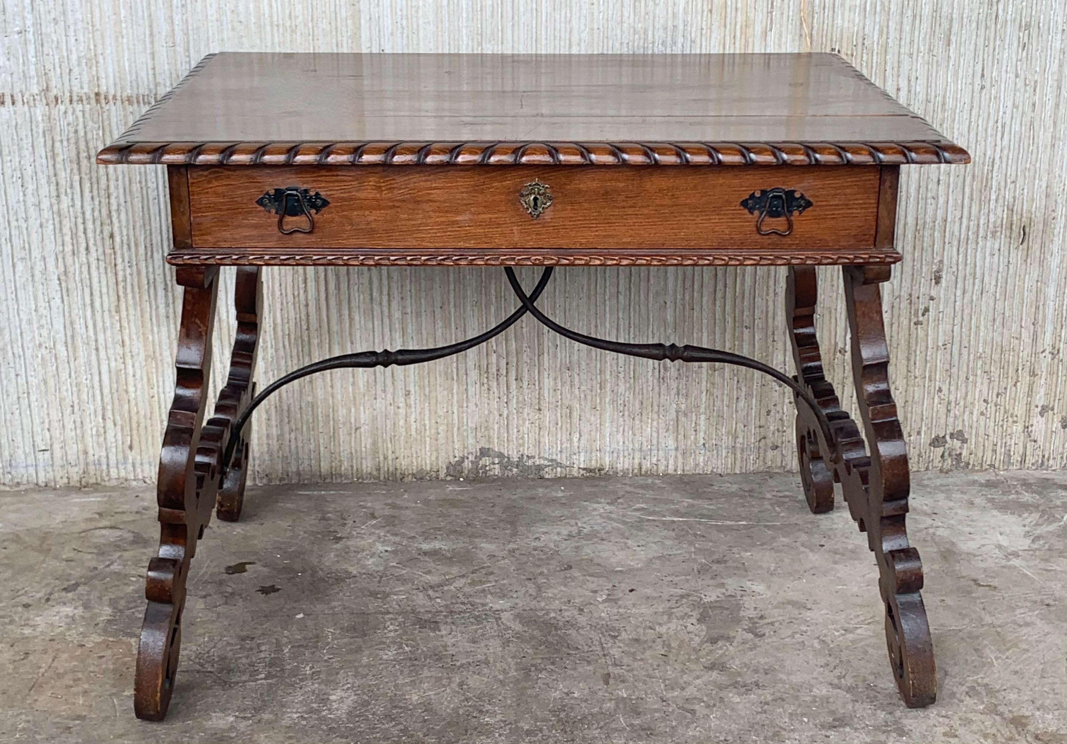 Early 20th Spanish desk with lyre legs and carved edges on top
An 20th century Spanish Baroque style desk, or writing table made of solid walnut with lyre shaped legs joined by wrought iron stretchers. Hand carved decoration across the front and