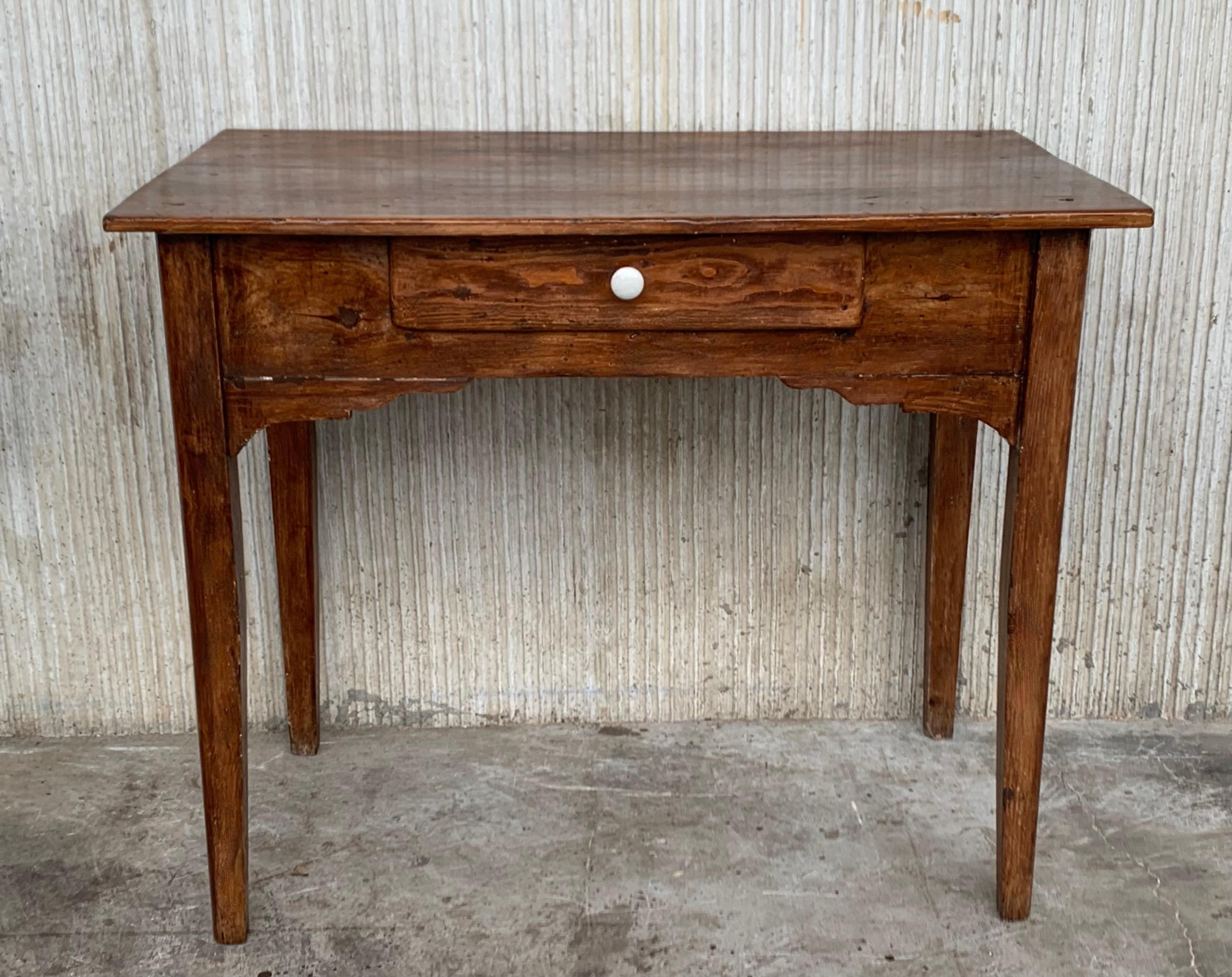 A charming early 20th century Spanish pine farm table with four tapered legs and a wonderfully well-worn finish from a century of use. Table works well for dining, but can also be used as a desk.

Height from the floor to the drawers. 24.80in.