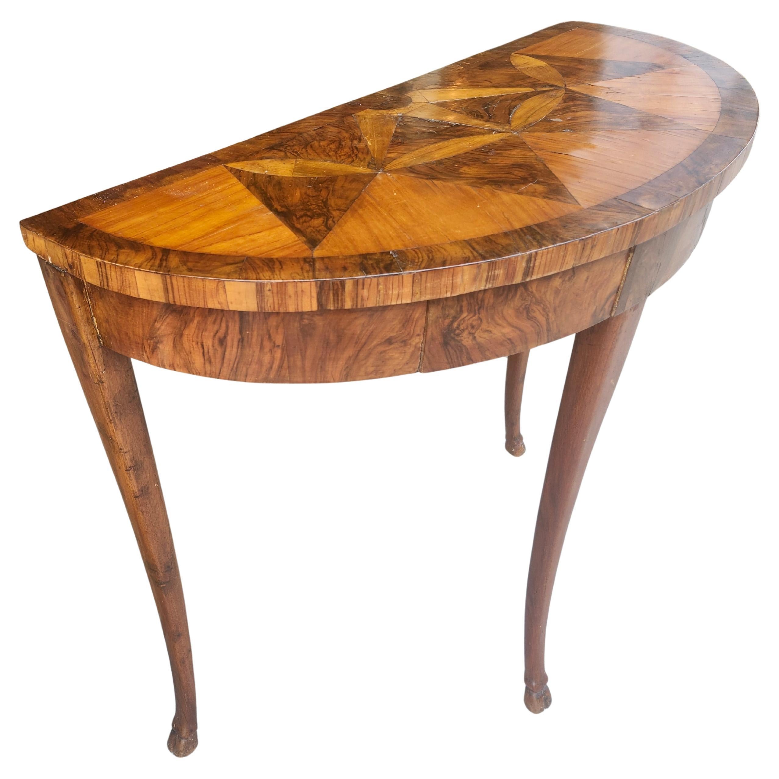 Petite (33 de large, 15 de profondeur) console démilune avec deux tiroirs pour vos affaires de tous les jours, clés, portefeuille ou autres. Motif incrusté sur le dessus et bande sur le bord. Pieds en forme de sabot. Usure normale du plateau, une