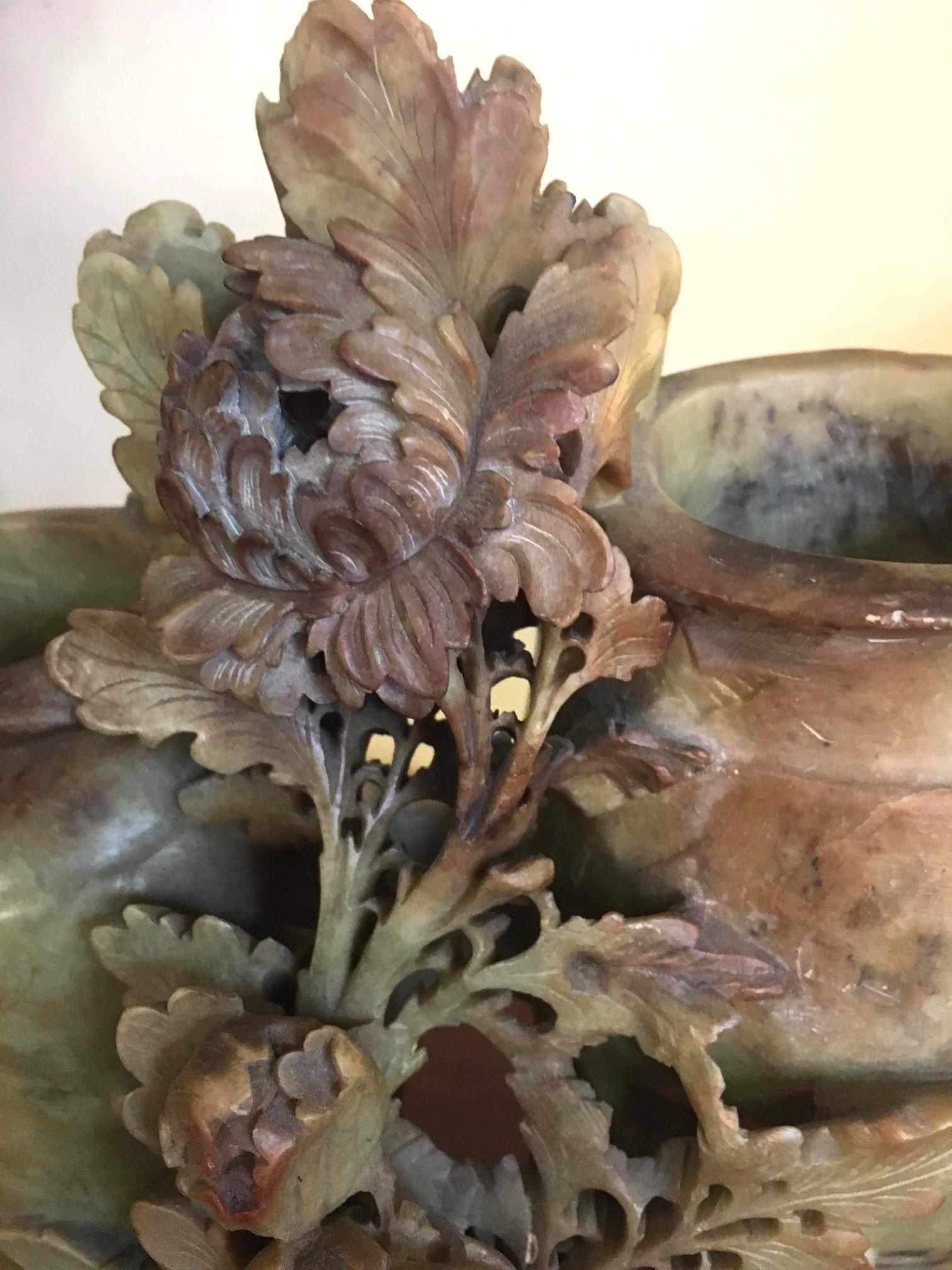This very lovely soapstone sculpture is intricately carved and features two vases and a smaller receptacle with three little birds intertwined in flowers and leaves. Some design etching on the larger vases. Contemporary teakwood stand. Measurements