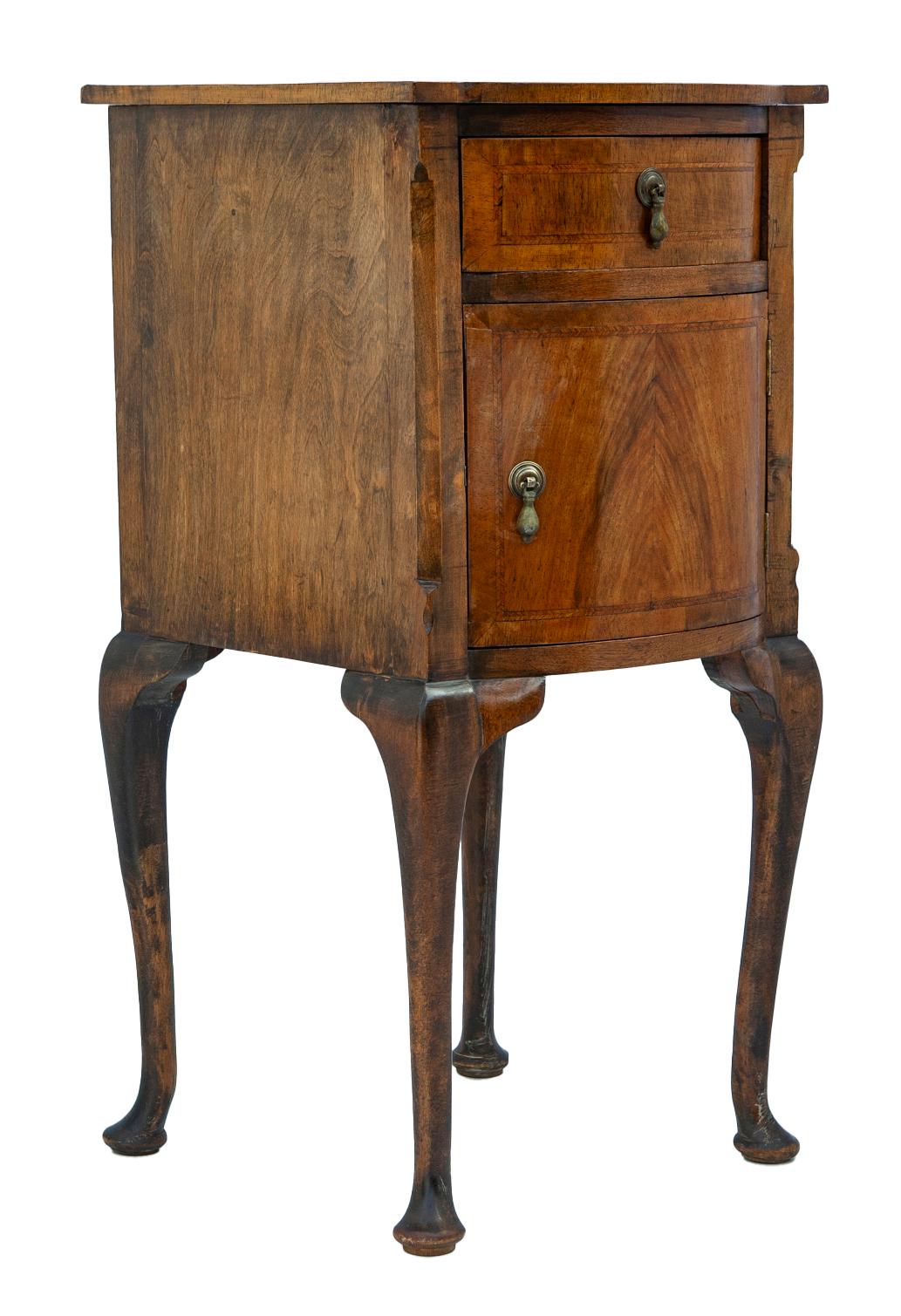 Comodino in noce francese con bordo finemente intarsiato e anta burattata.
Il comodino è dotato di un cassetto e di un'anta, entrambi con tiretti in metallo decorati. Si regge su eleganti gambe cabriole.