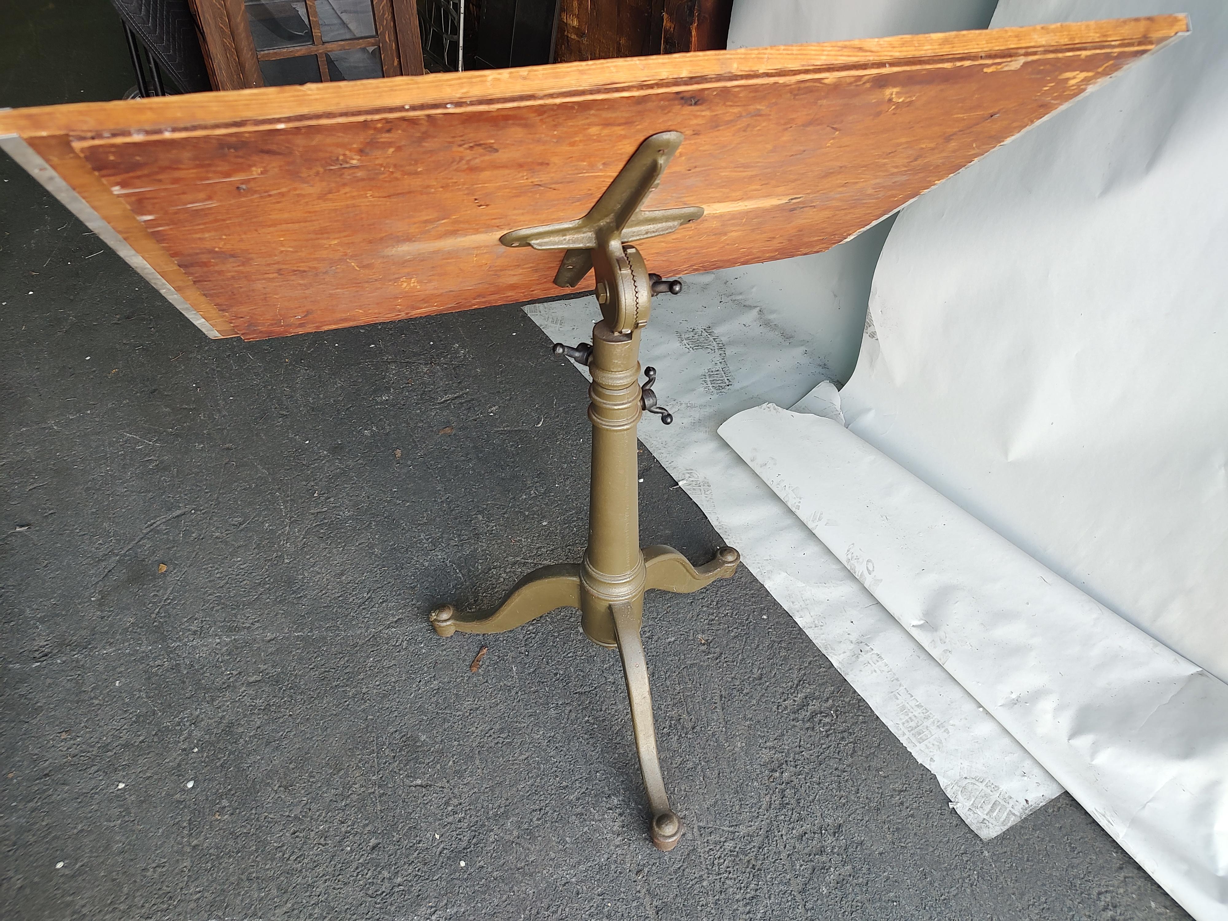 Amazing cast iron fully adjustable drafting table with a extreme height of 53 from a low of 39.5. In a original paint finish of army green with black cast iron adjustment knobs. Wood top which shows wear and is 36 x 24.25. Excellent vintage antique