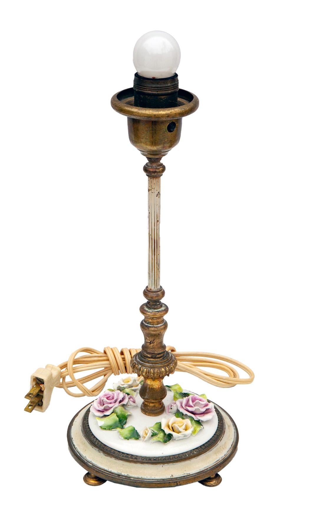 Charming & romantic pair of petite bedside/ vanity lamps. Handmade porcelain leaves & flowers sit on a porcelain tray above the enameled brass footed base.
Aged brass casings with new wiring using the original sockets.
The hand smocked silk shades