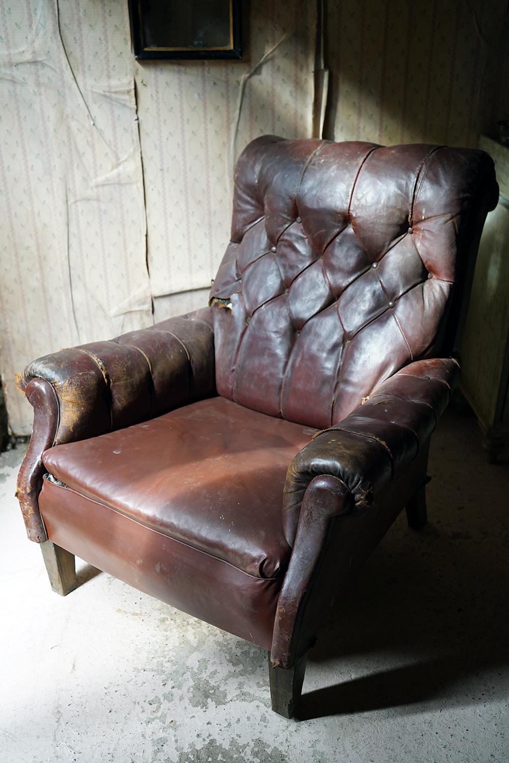 The comfortable and rather large armchair with a good scrolled back the whole in chestnut brown leather and rexine, having a button upholstered back and flanks, and scrolled arms to tapering oak legs and surviving from the first quarter of the