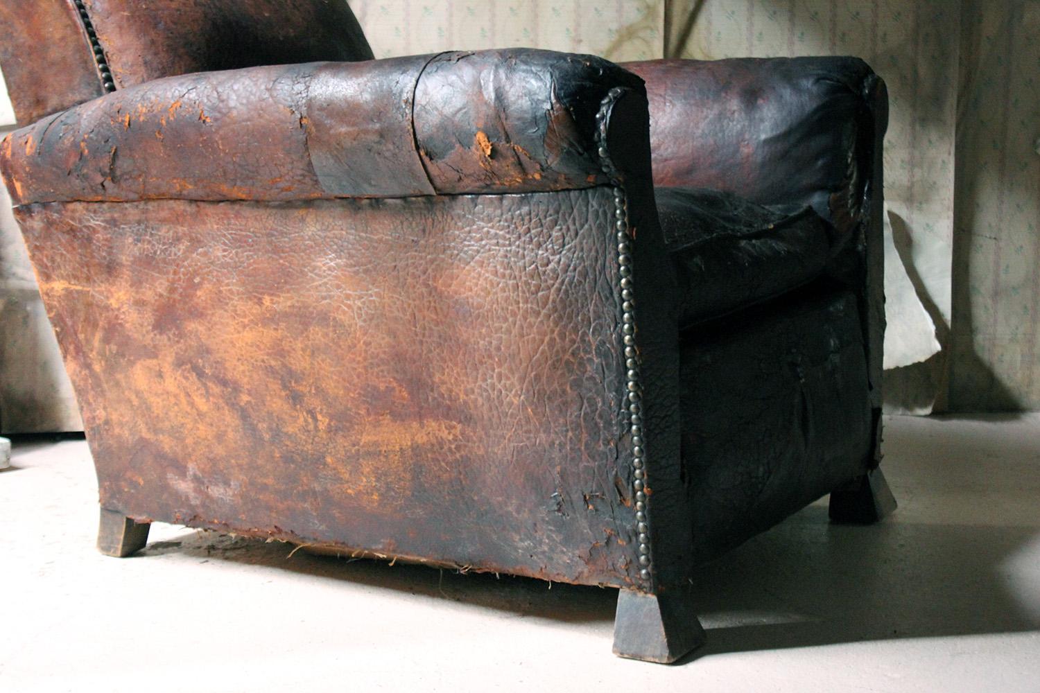 The comfortable and deep leather armchair having barrel type arms, the whole being hob-nail studded, and of typical club form, the feet being Art Deco inspired angular pyramid blocks, and the whole surviving from the early 20th century.
 
The