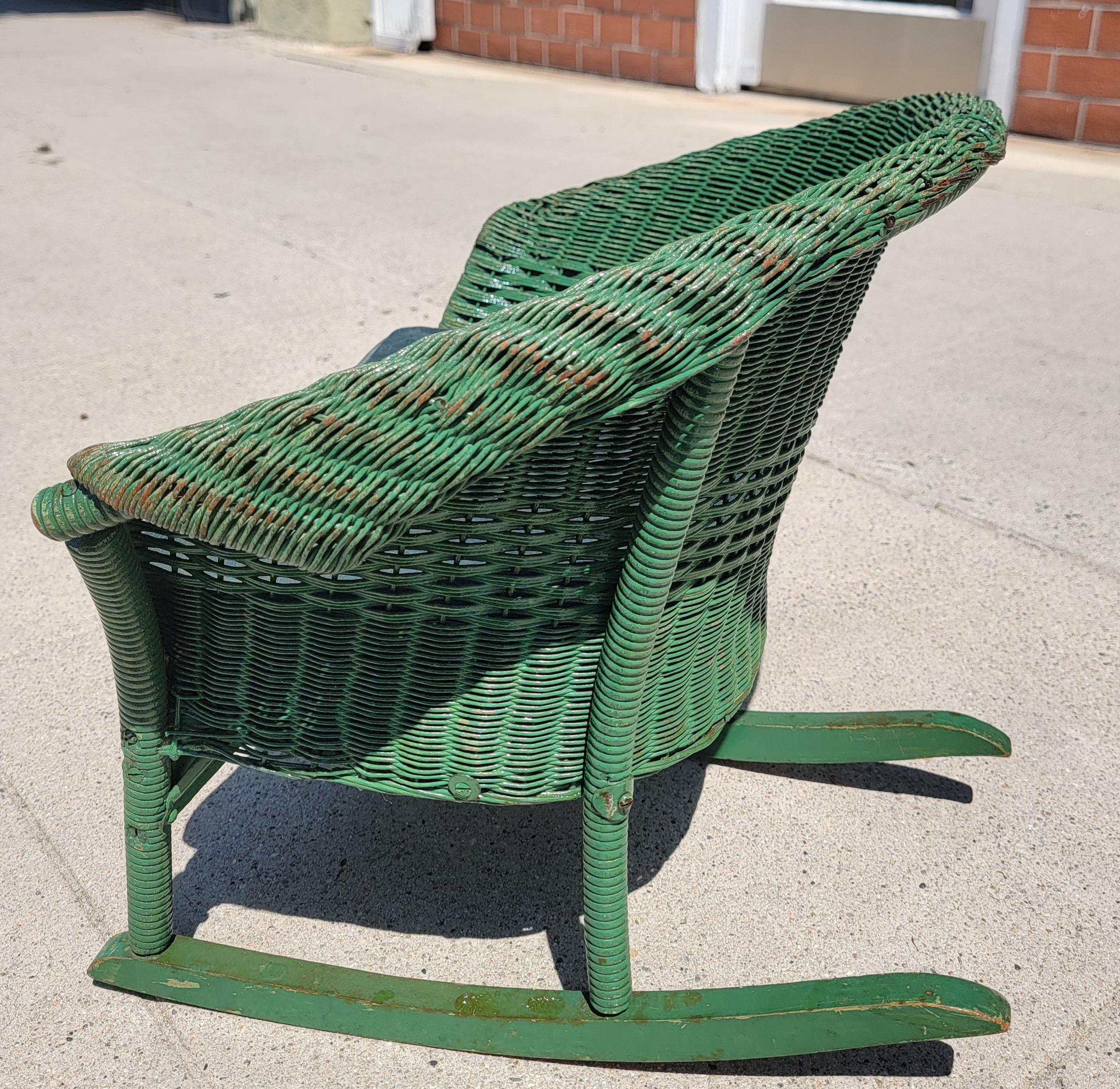 This original apple green painted child's wicker rocking chair is in fine condition.It has been coated with all weather protector varnish and has a dark green suede seat cushion.