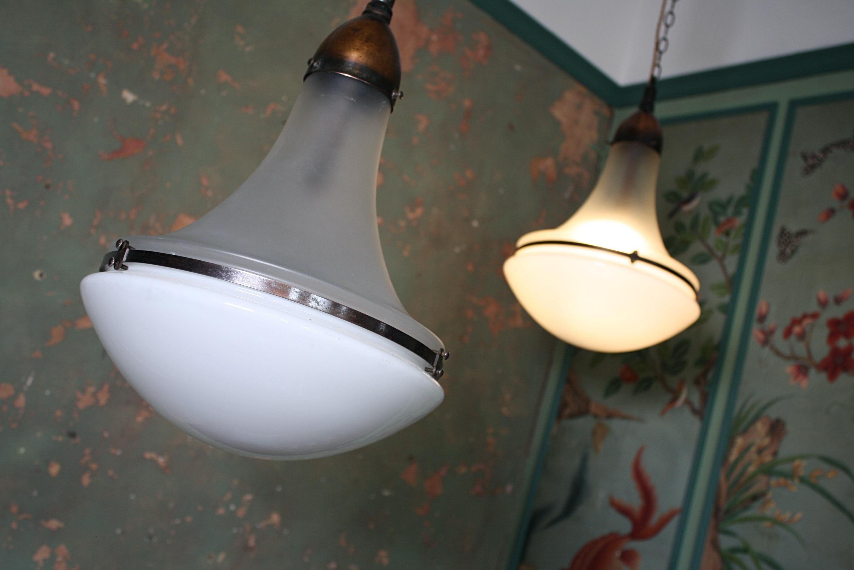A rare matching pair of large Peter Behrens pendants, with a copper galleries and central bands, early 20th century.

Frosted glass top sections, with a opaline bowls/diffusers,

circa 1920.

The lights comes with their original ceiling roses,