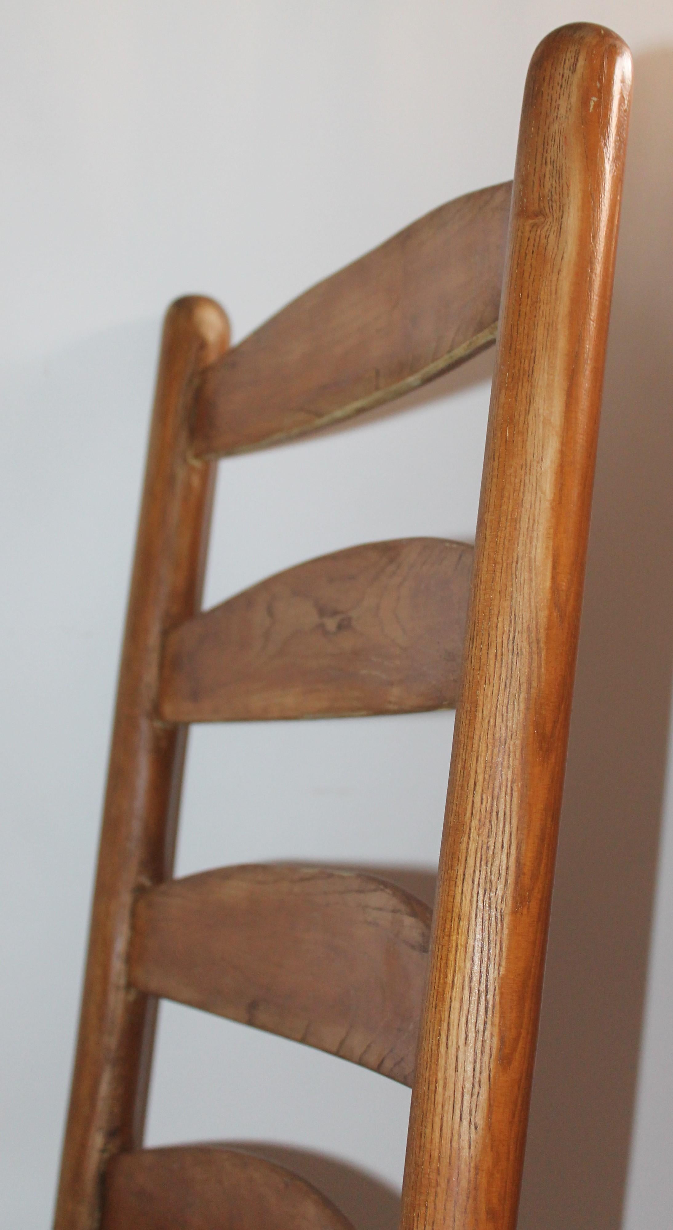 This fun and folky mid western ladder back rocking chair is in fine, worn good condition. The original worn patina on the smooth pine wood is fantastic and the sturdy cowhide seat is original to the chair.