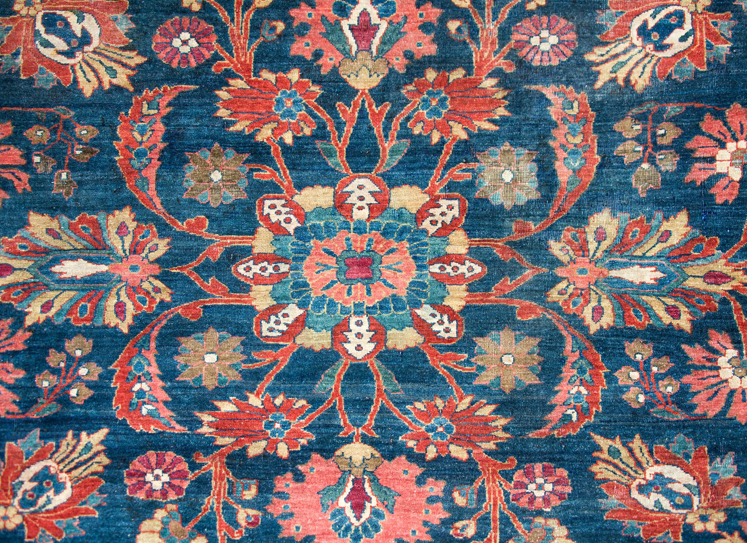 An incredible early 20th century Persian Mohajeran rug with a beautiful central floral medallion living amidst a field of scrolling vines and myriad flowers, surrounded by a complex border with a wide central floral patterned center stripe flanked