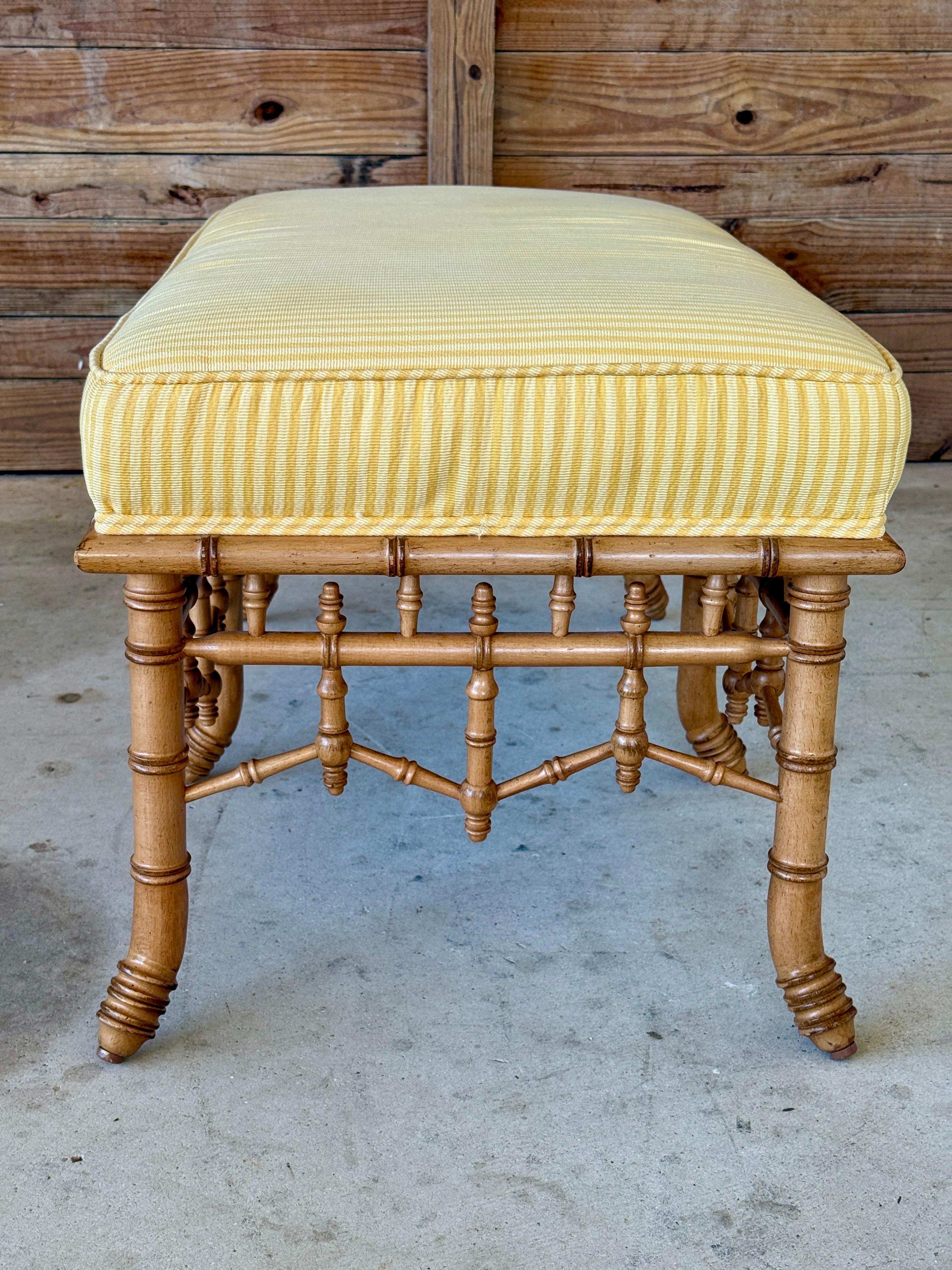 Un precioso banco de Schumacher Furniture, con una base de madera tallada de imitación de bambú y detalles de huso. Tapizada en una tela Schumacher de rayas amarillas soleadas, esta pieza combina la artesanía intemporal con un aspecto fresco y